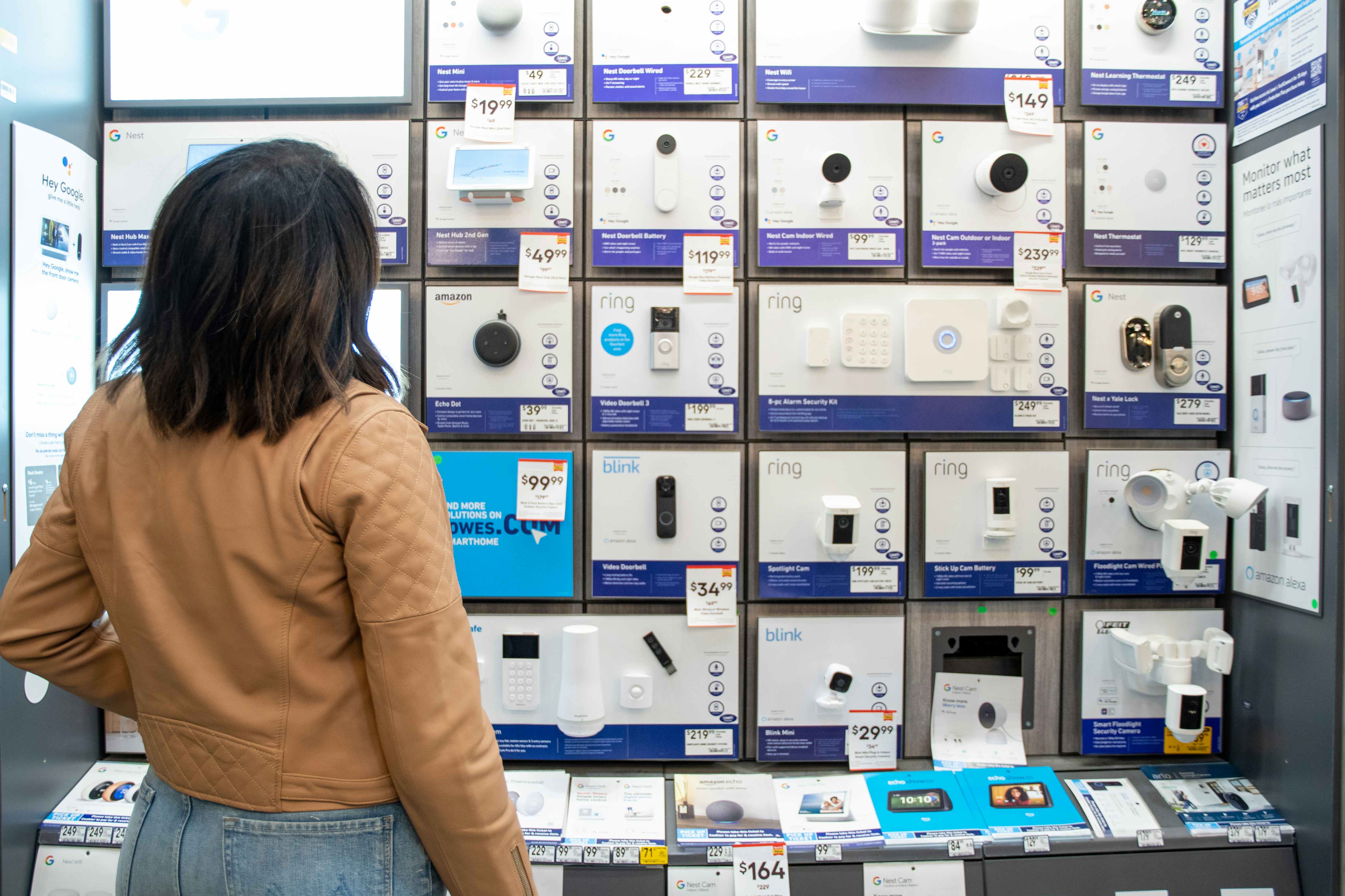 a woman looking at smart home devices on display at lowe's