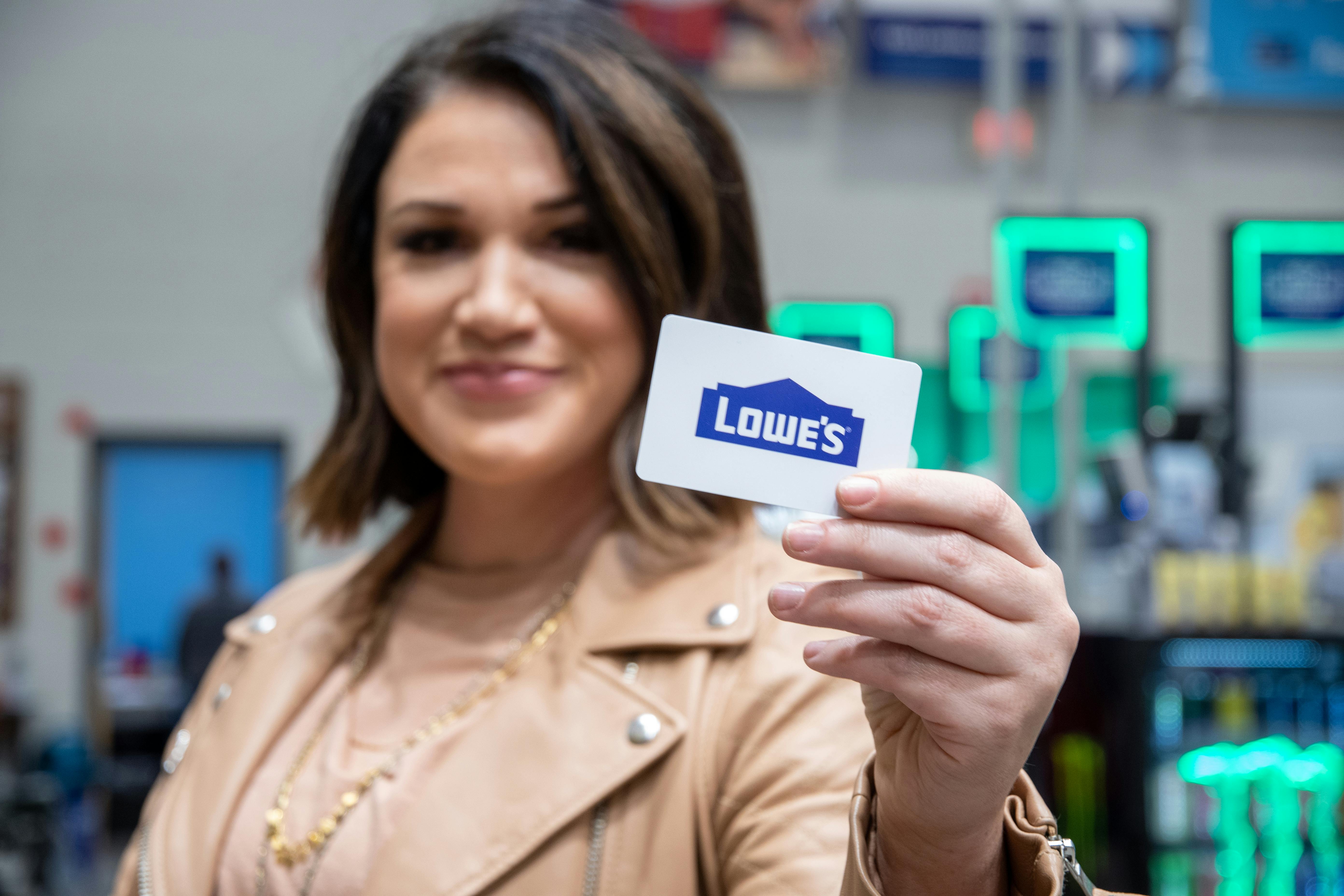 A person holding up a Lowe's gift card inside the store