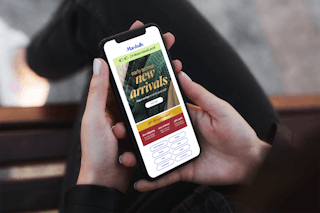 a woman looking at an email on her phone for early access to new Marshalls online arrivals
