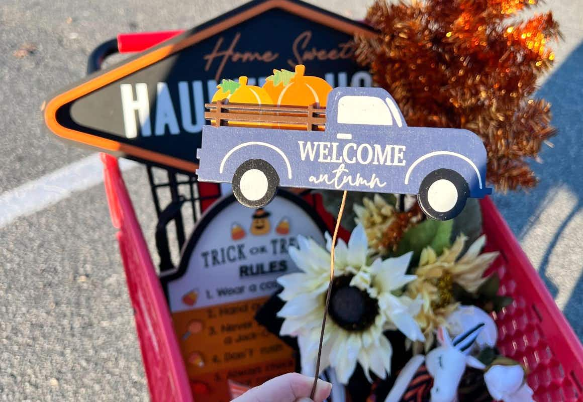 someone holding up a blue truck that says welcome autumn