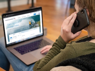 A person on the American Airlines website on a laptop, calling to book a flight