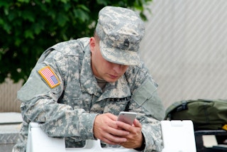 A man in a military uniform looking at a cell phone.