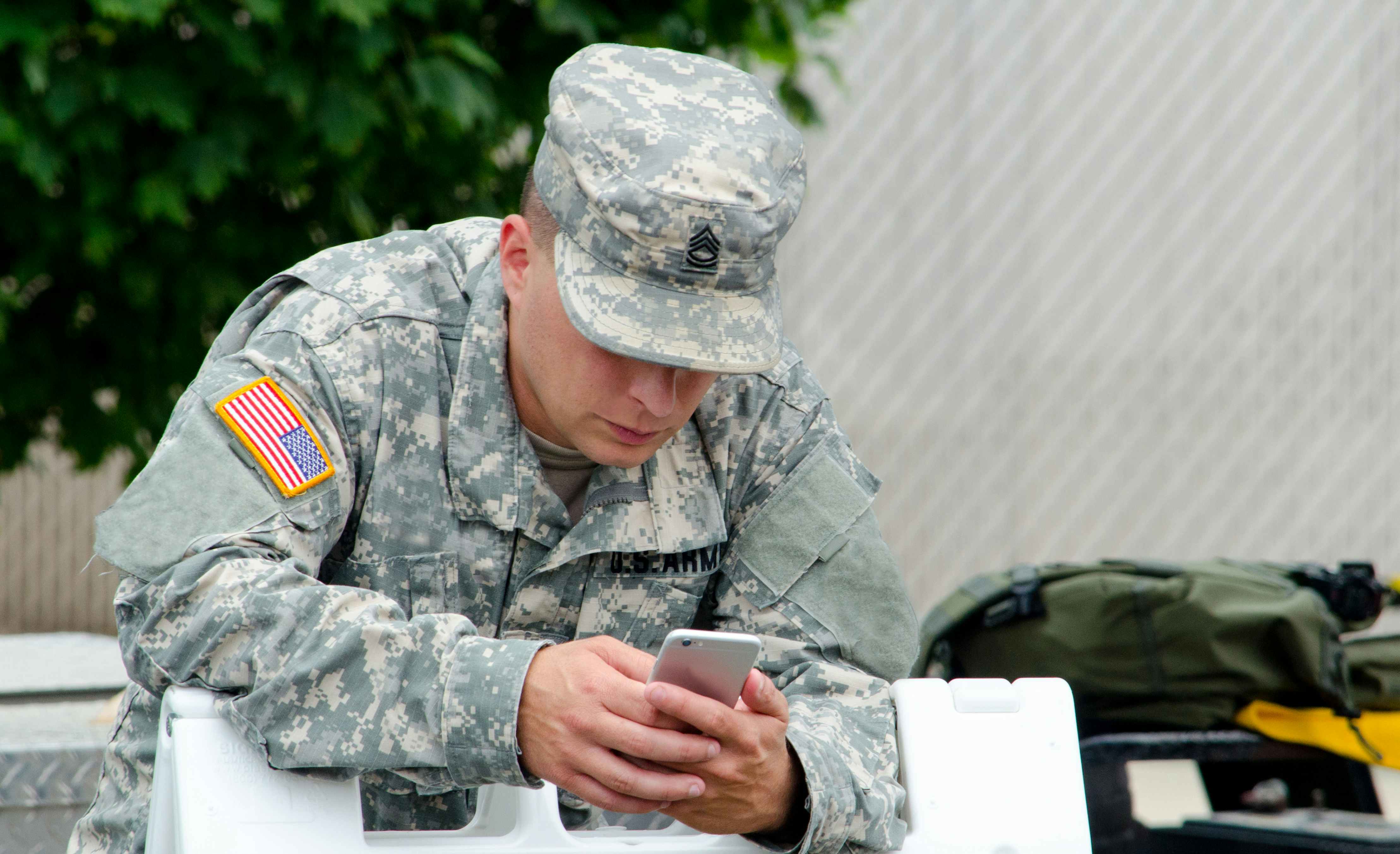 A man in a military uniform looking at a cell phone.
