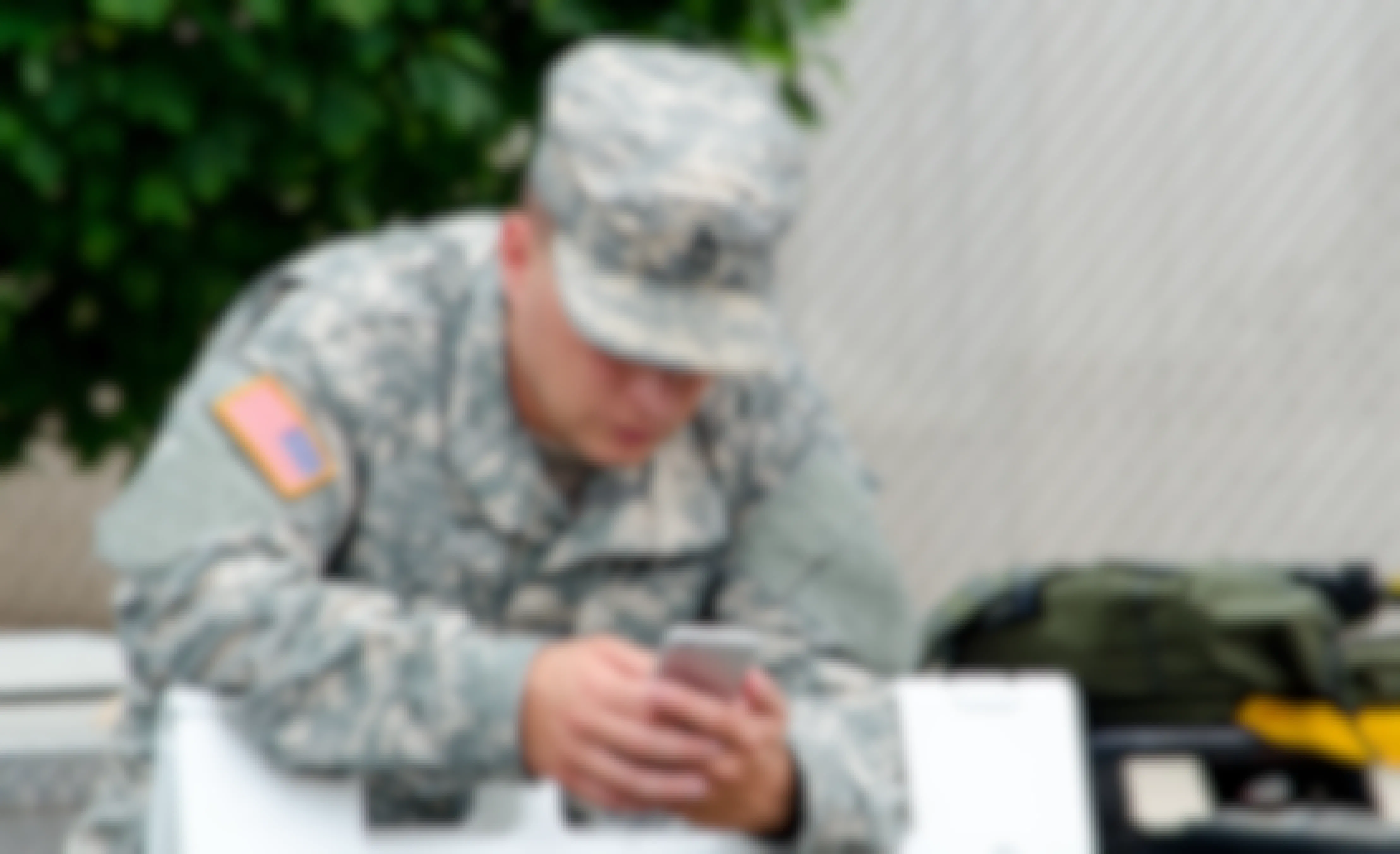 A man in a military uniform looking at a cell phone.