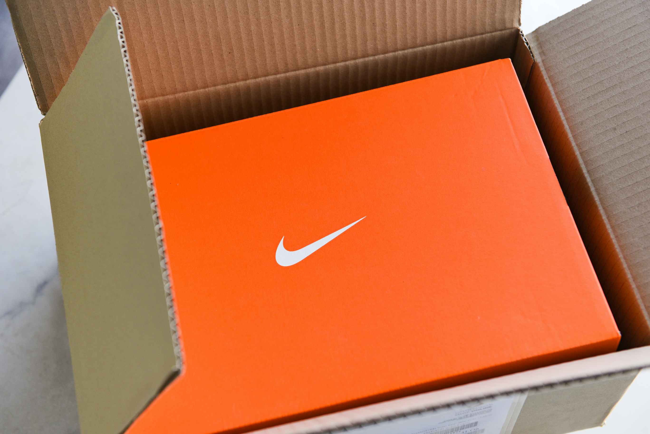 A box of Nike shoes sitting in a cardboard shipping box