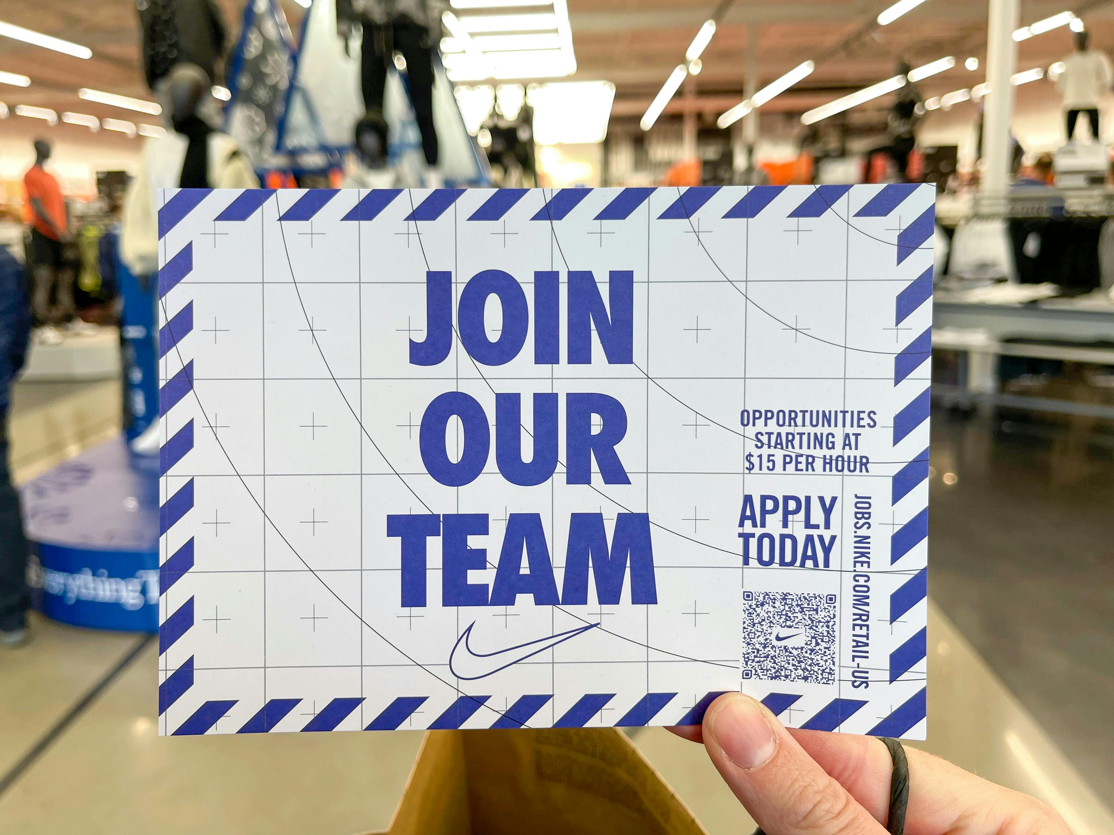 An information card for applying to work for Nike being held up in a Nike store. The card says, "Join our team