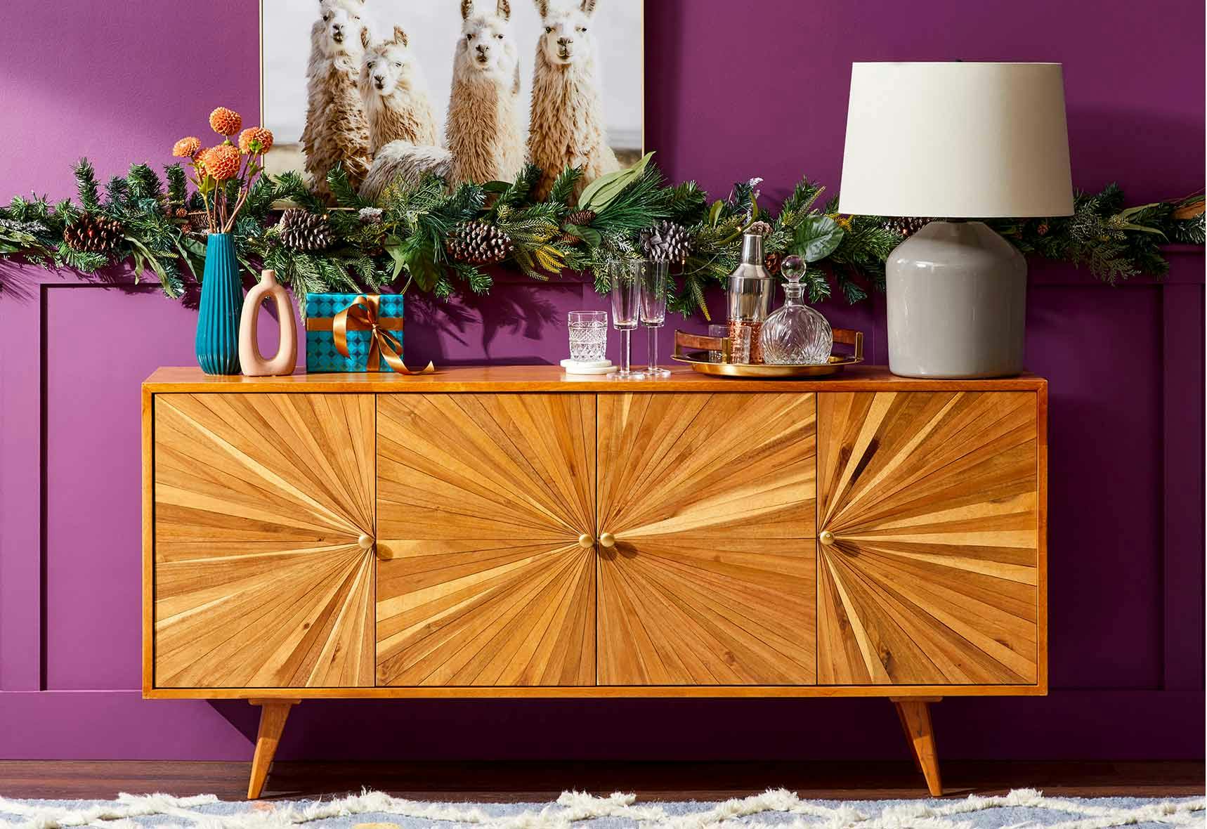 Brown wooden console table with christmas decorations against a purple wall.