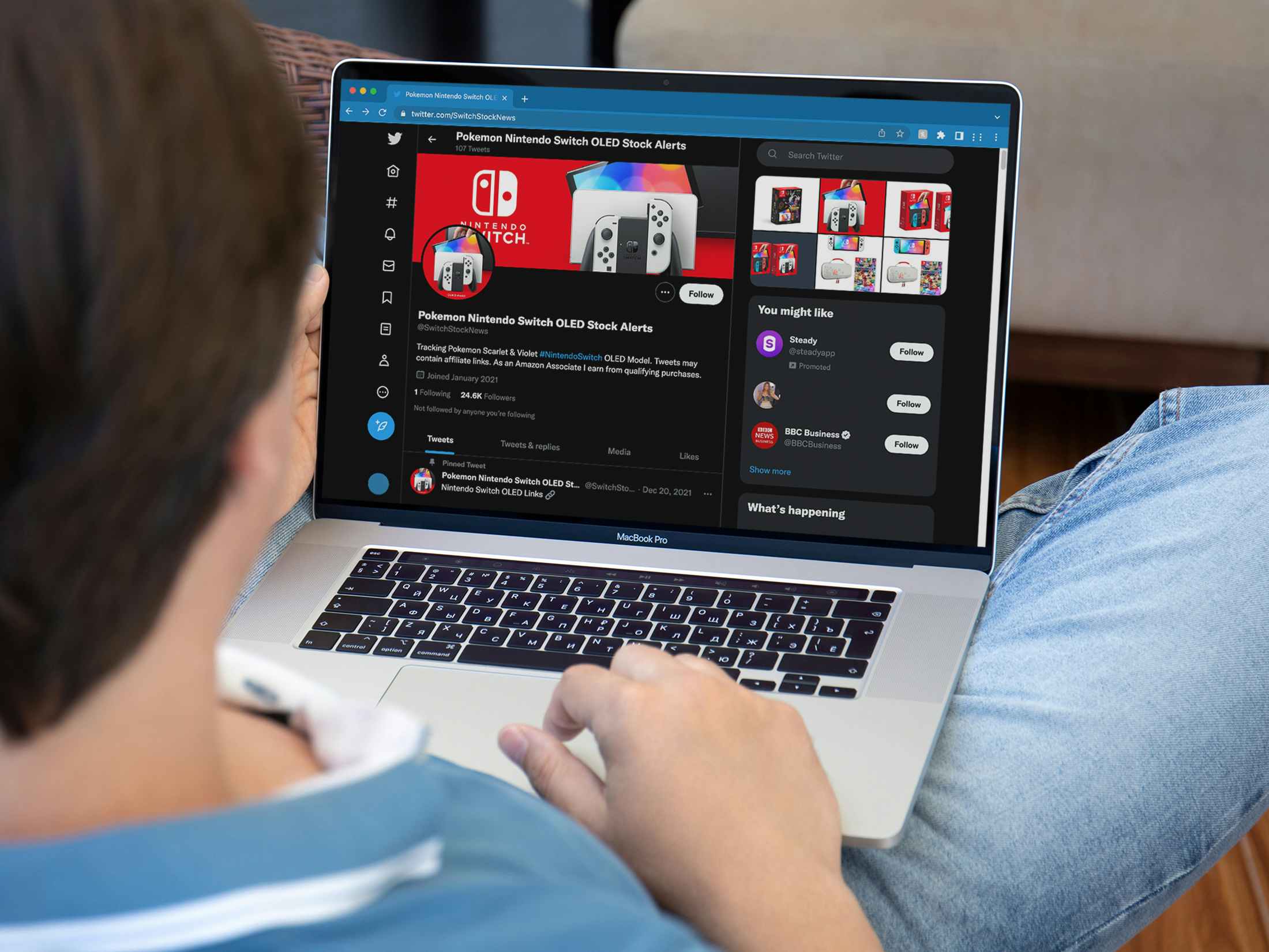 nintendo switch oled restock - A young person looking at the Twitter profile of SwitchStockNews on their laptop