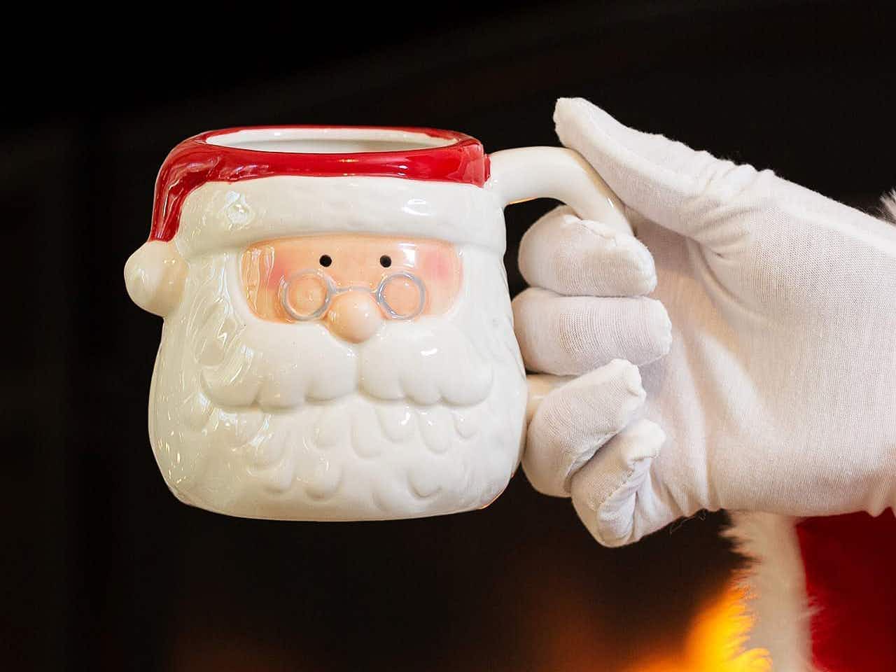 vintage santa mugs - A person's hand holding a Festive Face Santa Mug in front of a fireplace