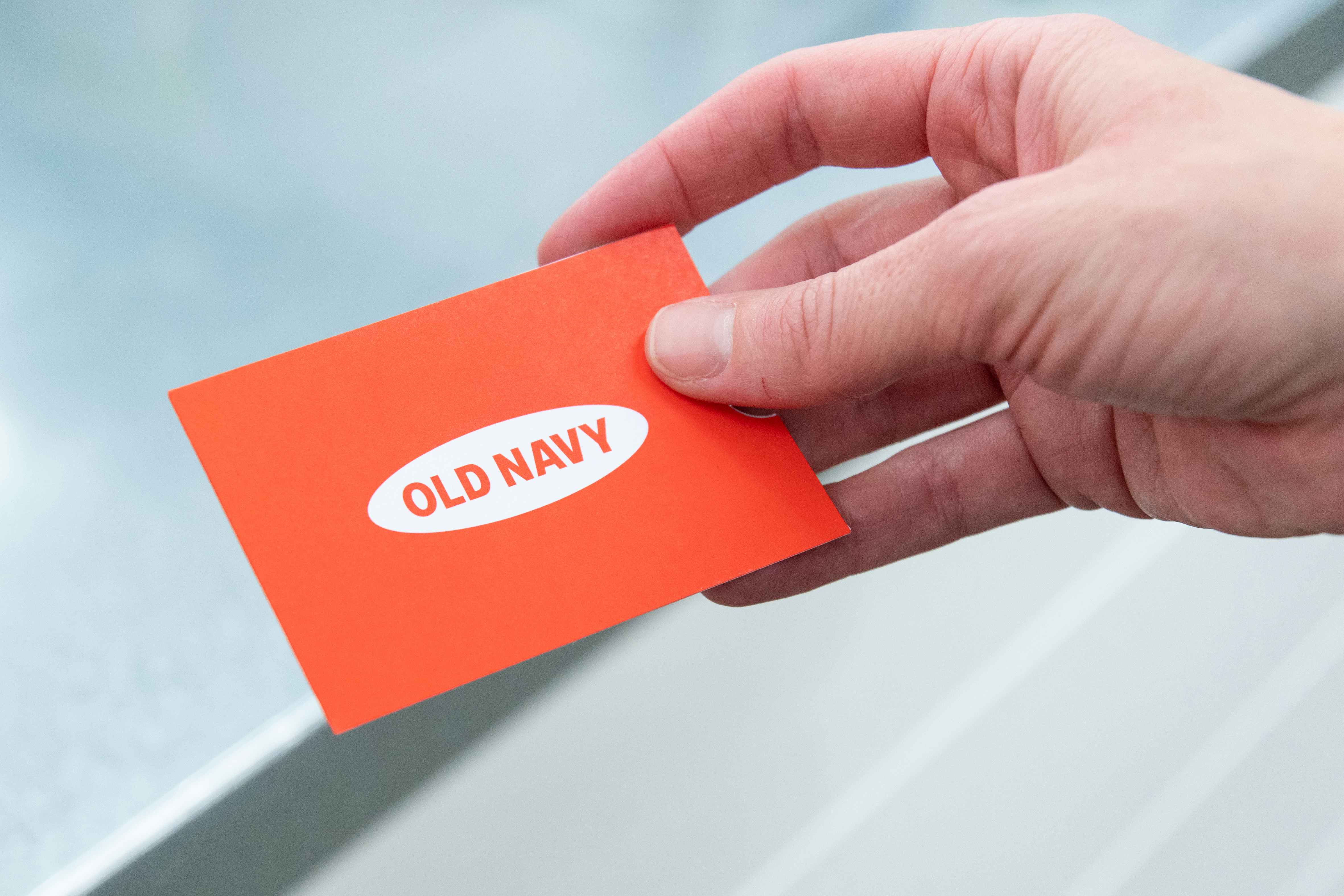 A close up on someone's hand holding an Old Navy gift card