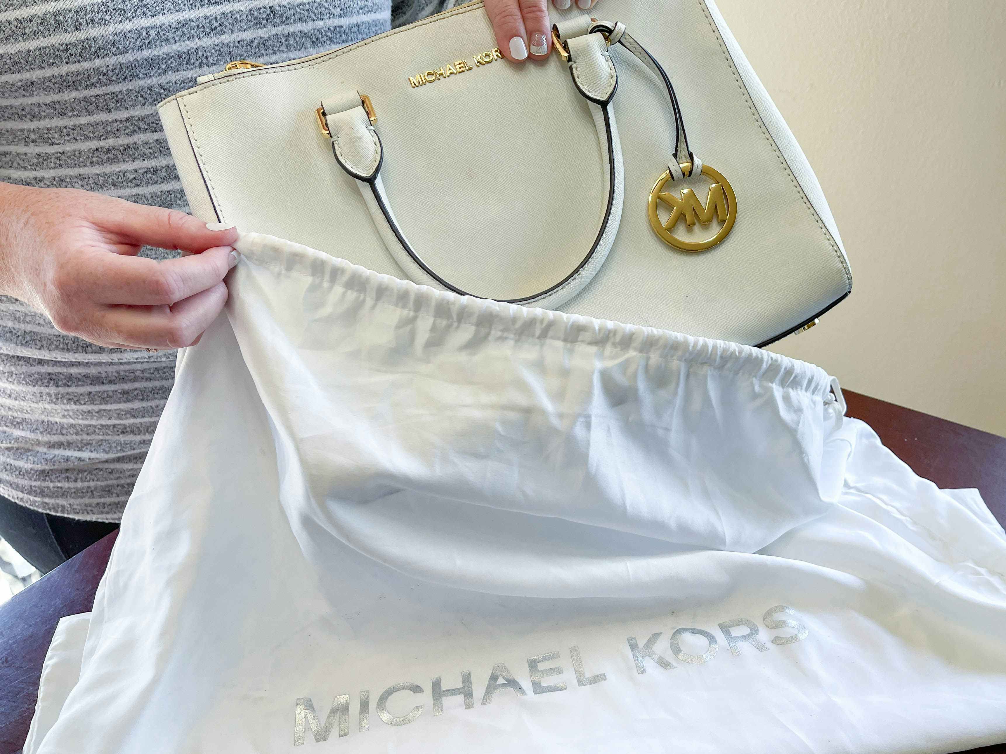 a person putting a michaels kors handbag in dust bag 