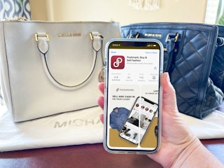 michael kors handbags on table with a person holding a sell phone with poshmark on screen