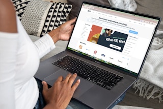 a person on a laptop looking up raise website while sitting on a couch 