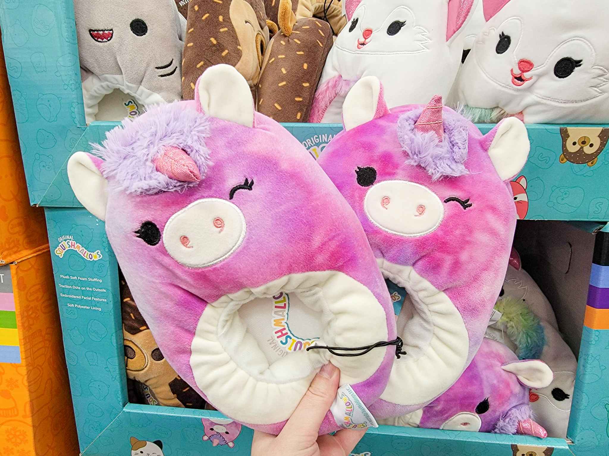 hand holding a pair of unicorn squishmallow slippers