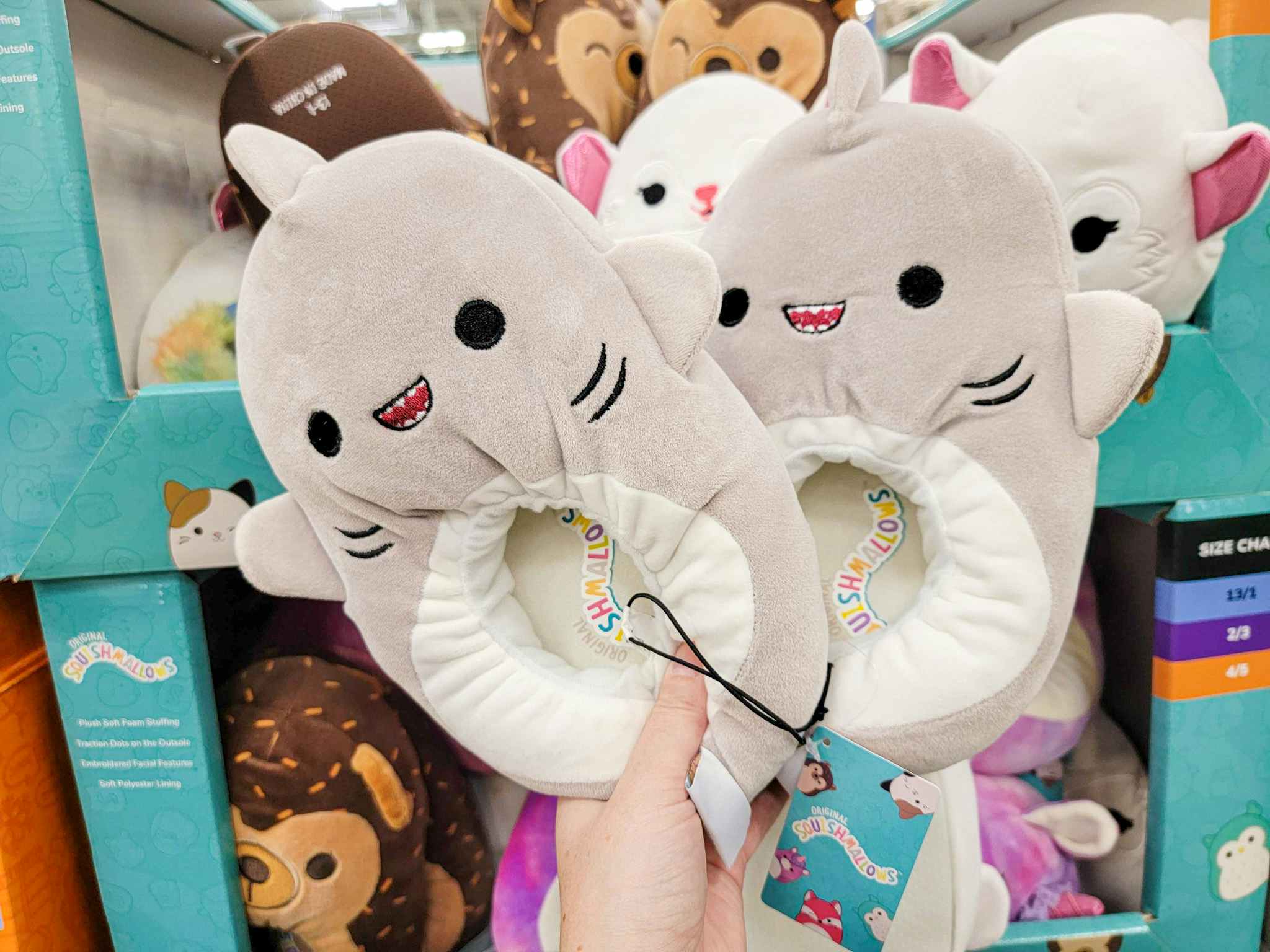 hand holding a pair of shark squishmallow slippers