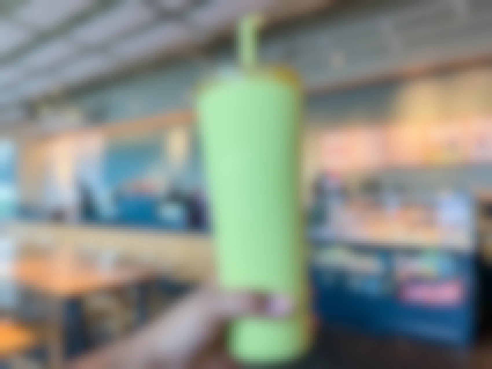 Person holding Starbucks green-yellow tumbler inside the cafe