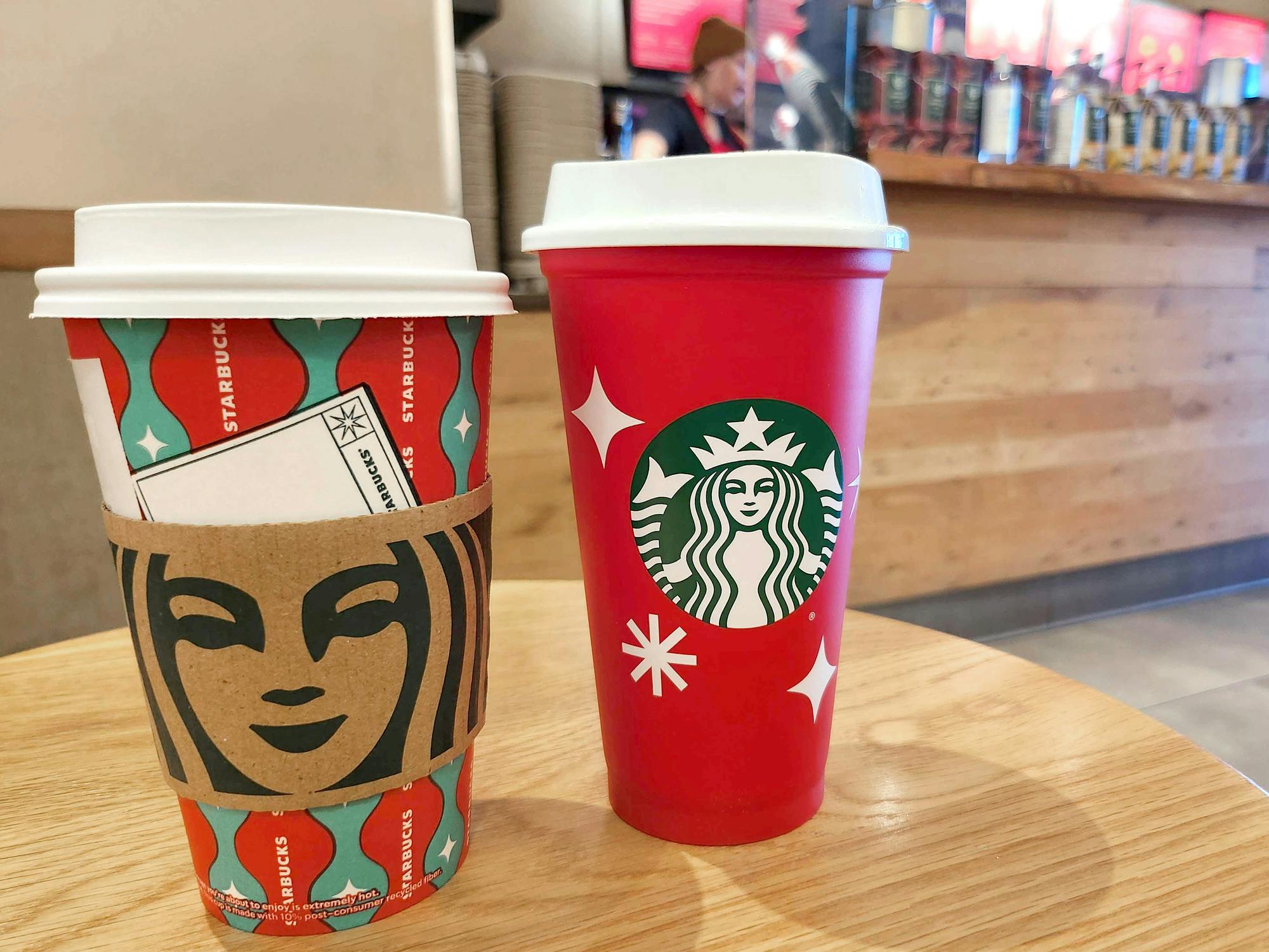 starbucks red cup next to holiday cup on table