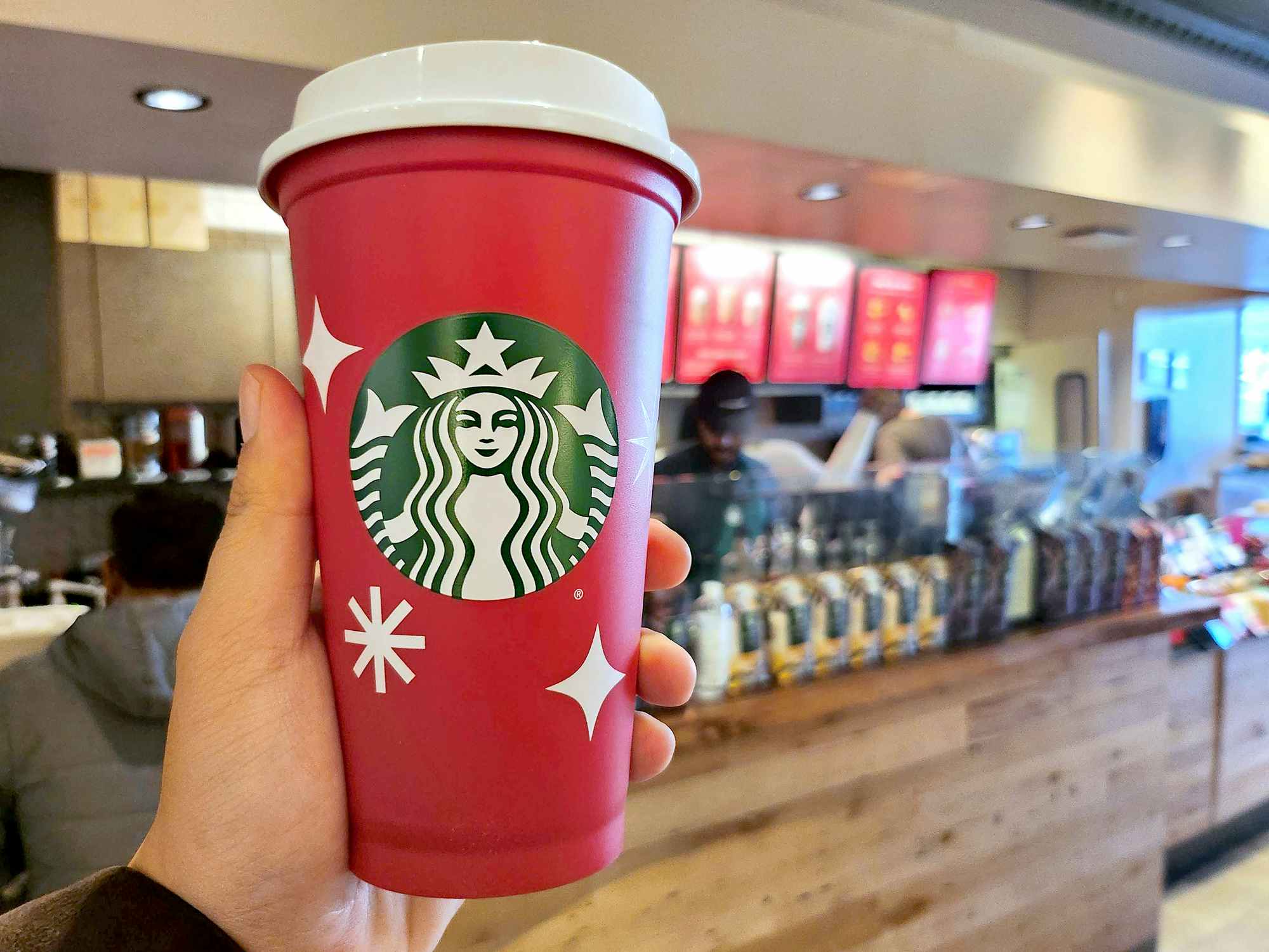 hand holding starbucks red cup in coffee shop