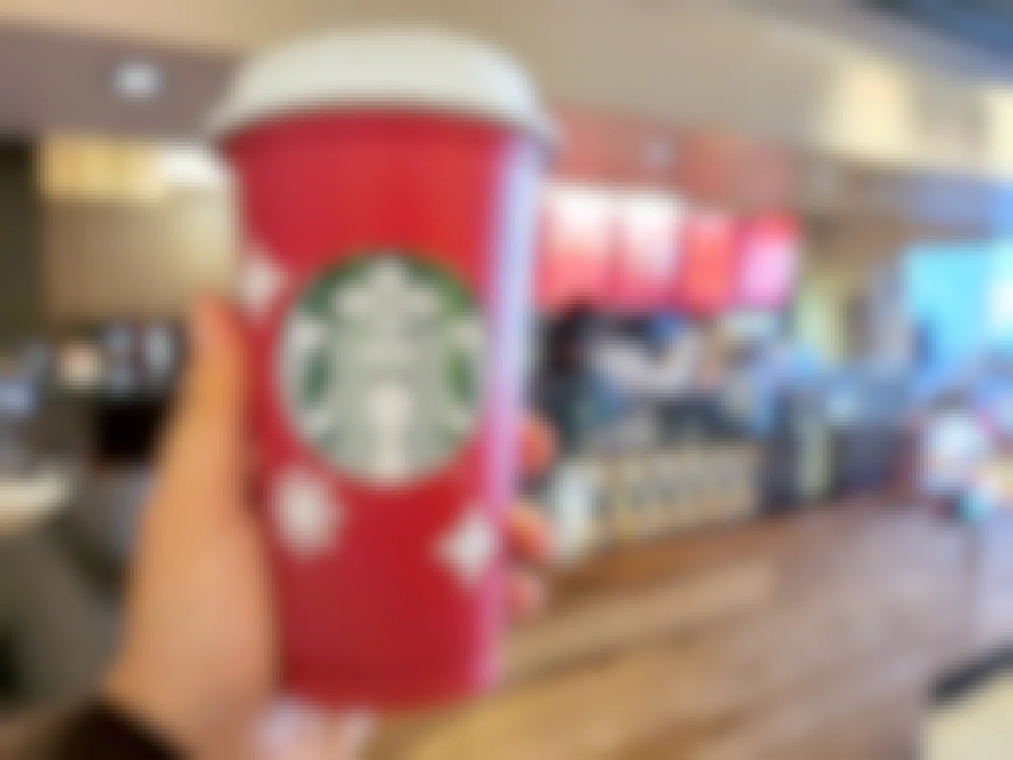 hand holding starbucks red cup in coffee shop