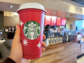 hand holding starbucks red cup in coffee shop