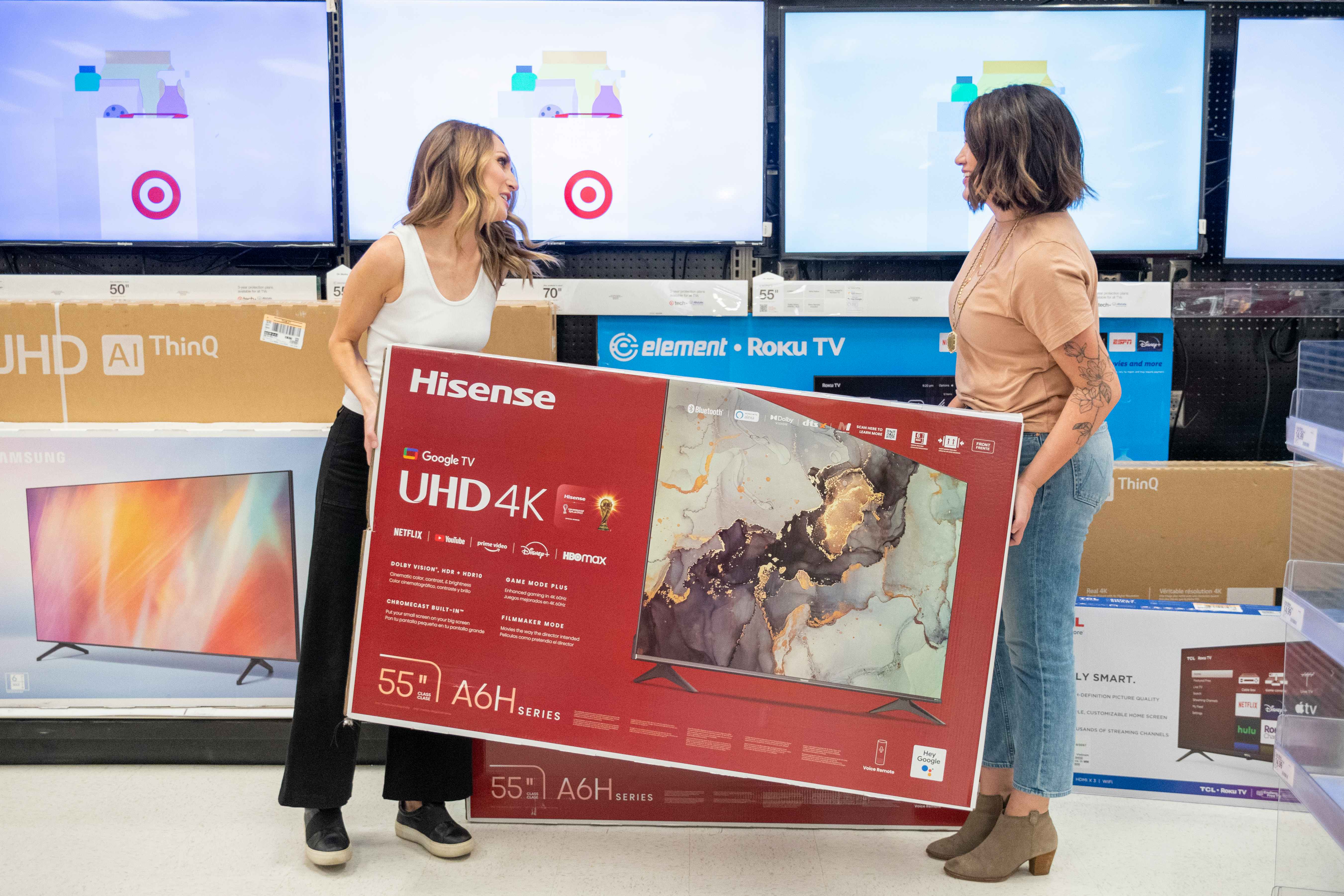 two women carrying a hisense smart tv at target