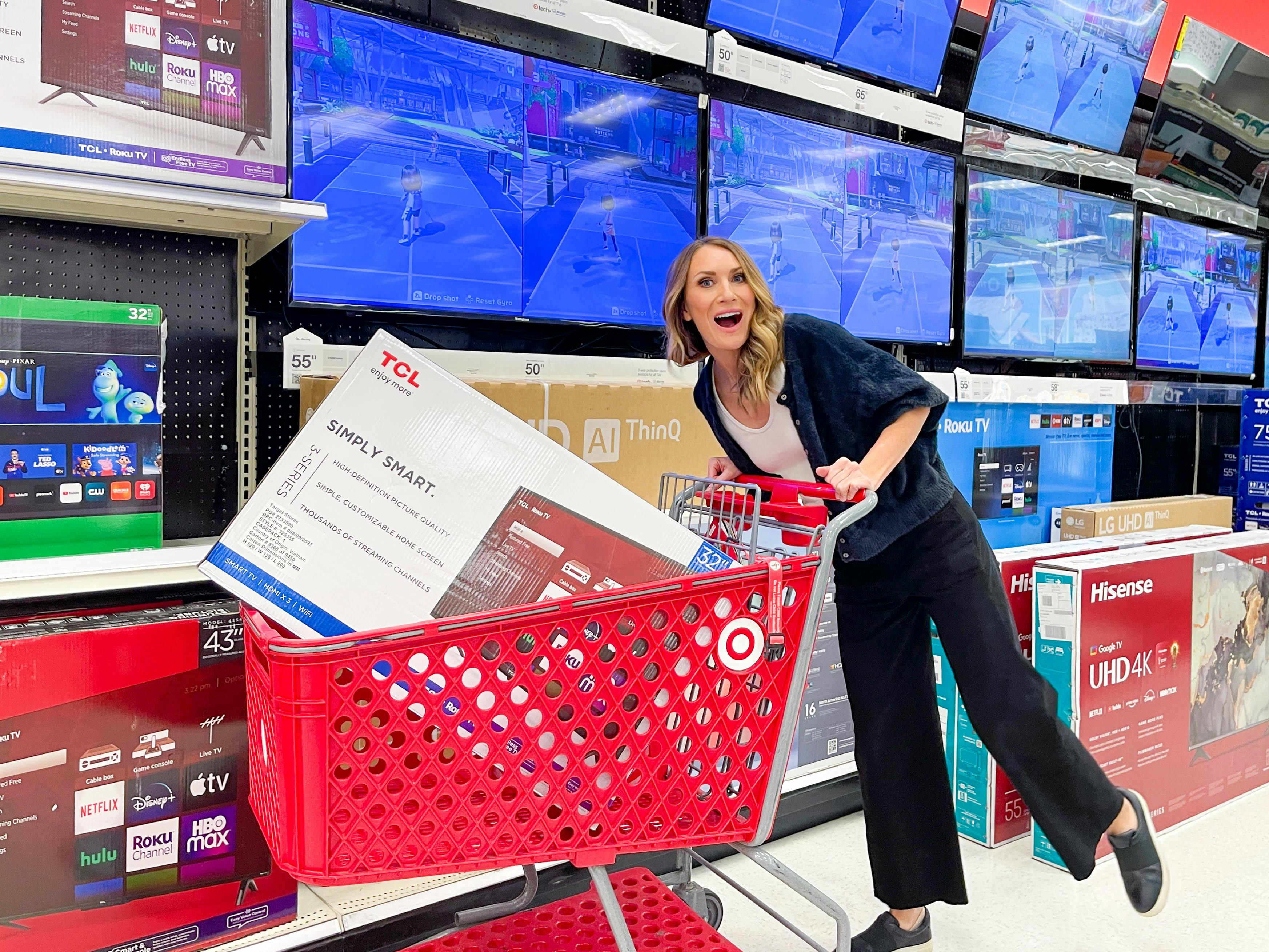 a woman pushing a Target cart with a TV in it