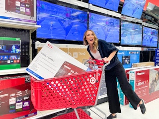 a woman pushing a Target cart with a TV in it