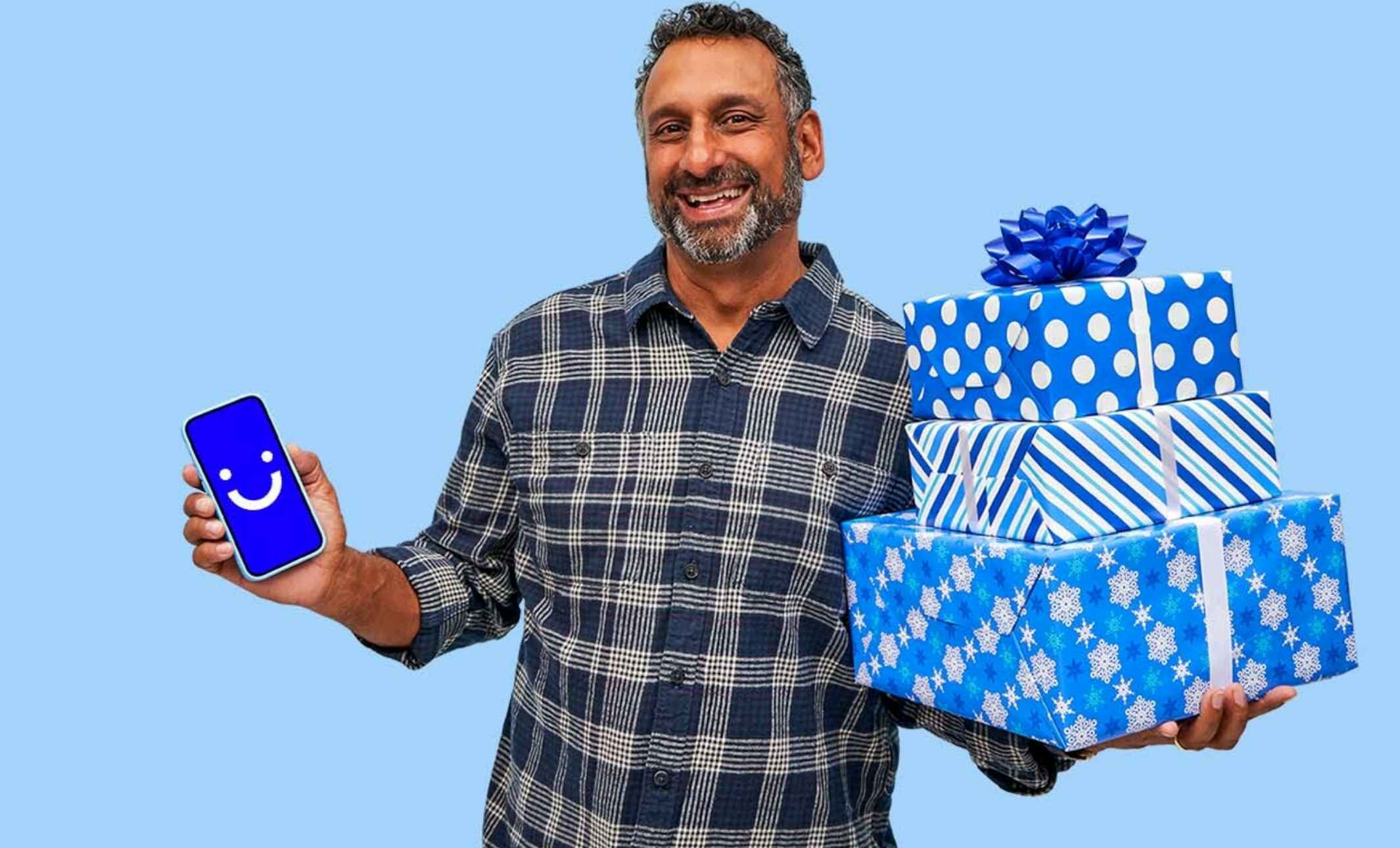 man holding a phone and a stack of presents