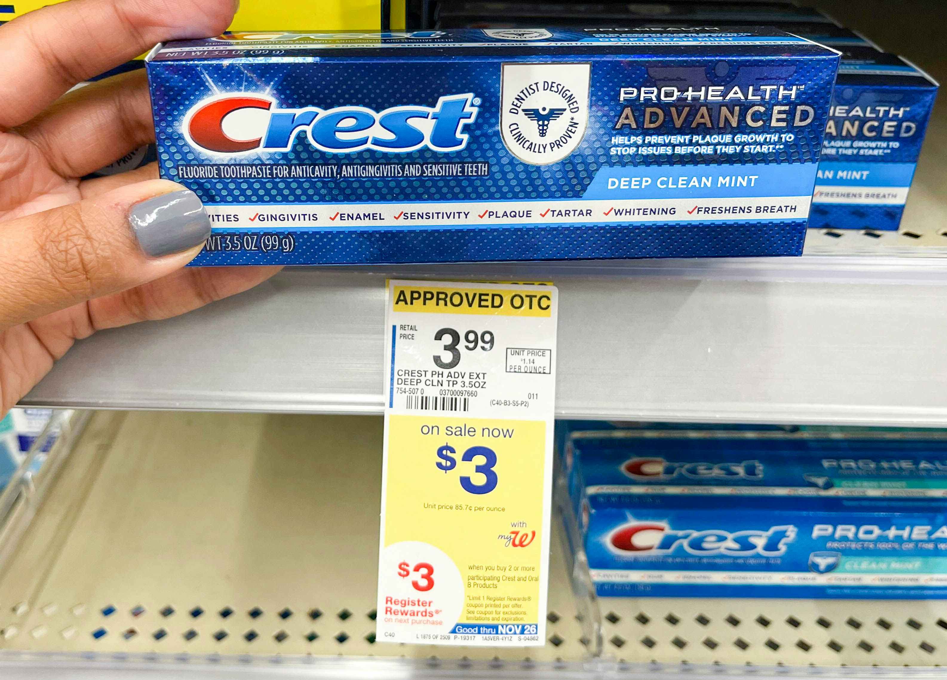 hand holding box of Crest toothpaste next to sales tag