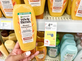hand holding a bottle of Garnier Whole Blends honey blend conditioner next to sales tag