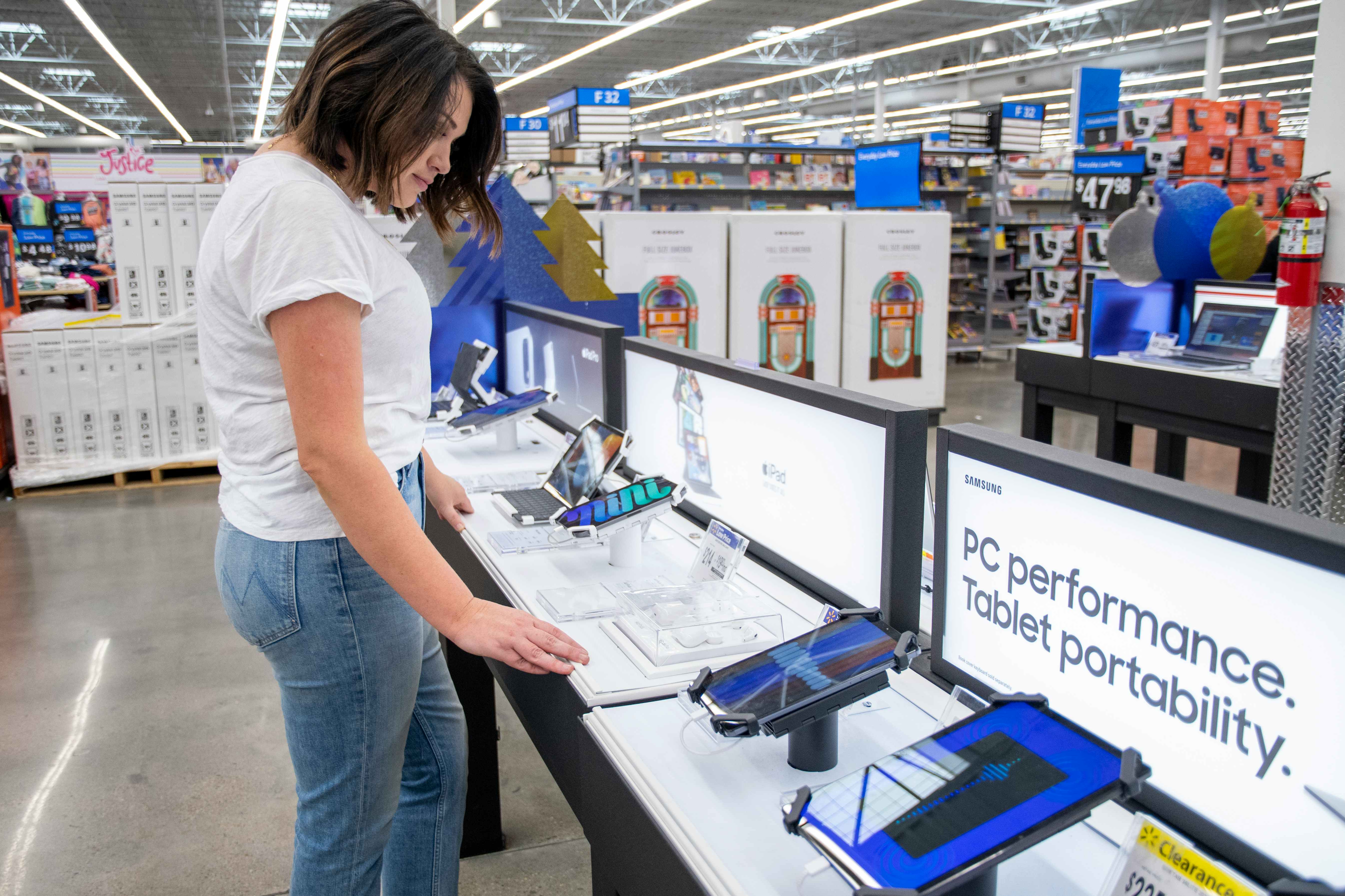 A woman looking at Samsung tablets in Walmart's electronics department