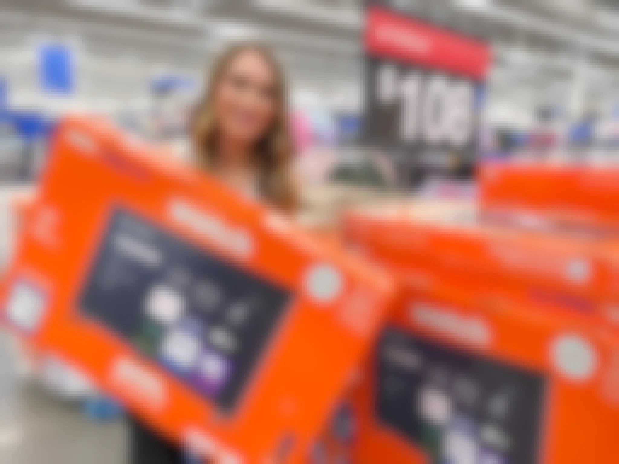 a woman holding an Onn smart TV next to an Onn TV display with a $108 sale price sign