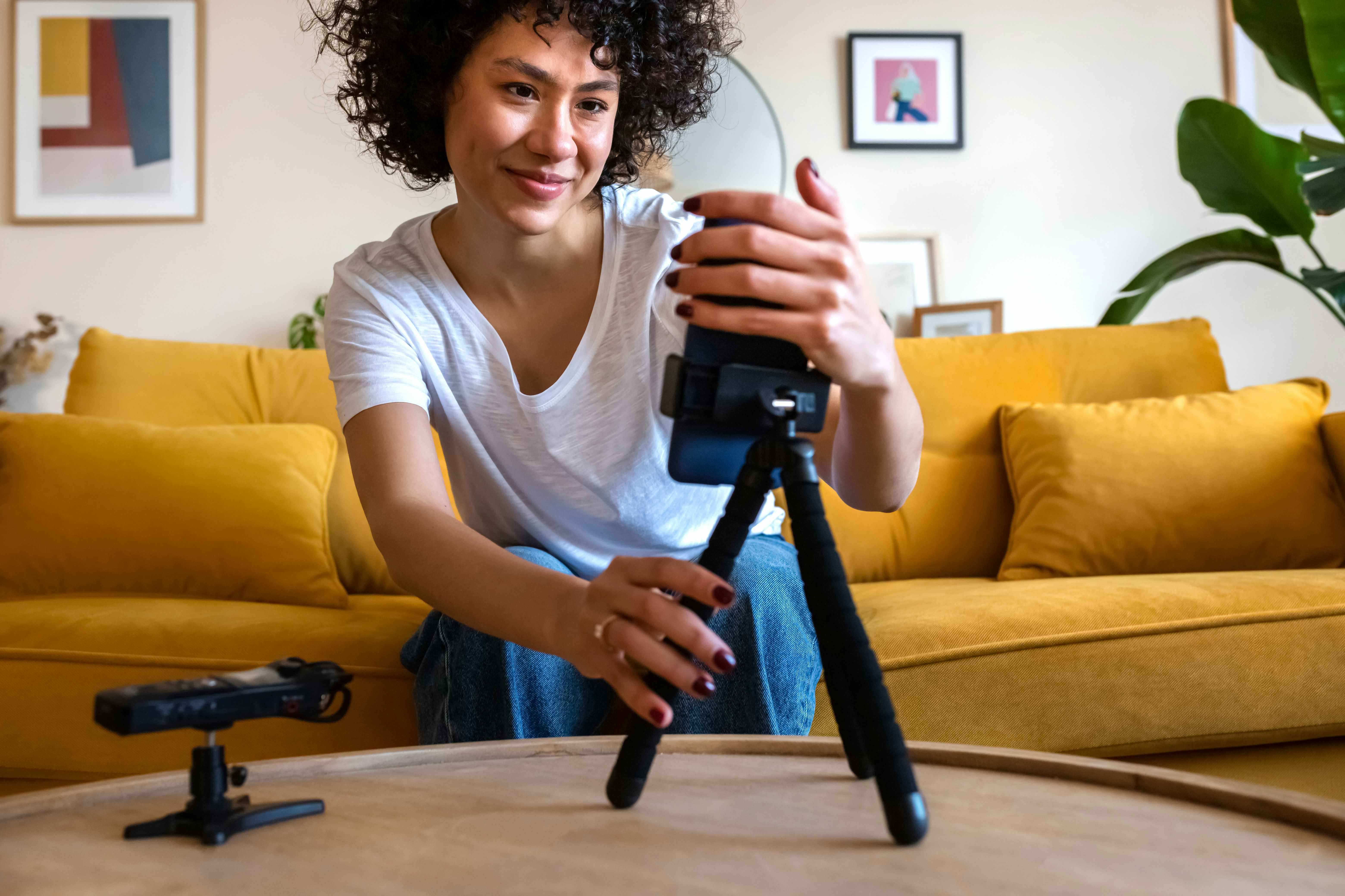 Woman setting up Camera while sitting on a yellow couch