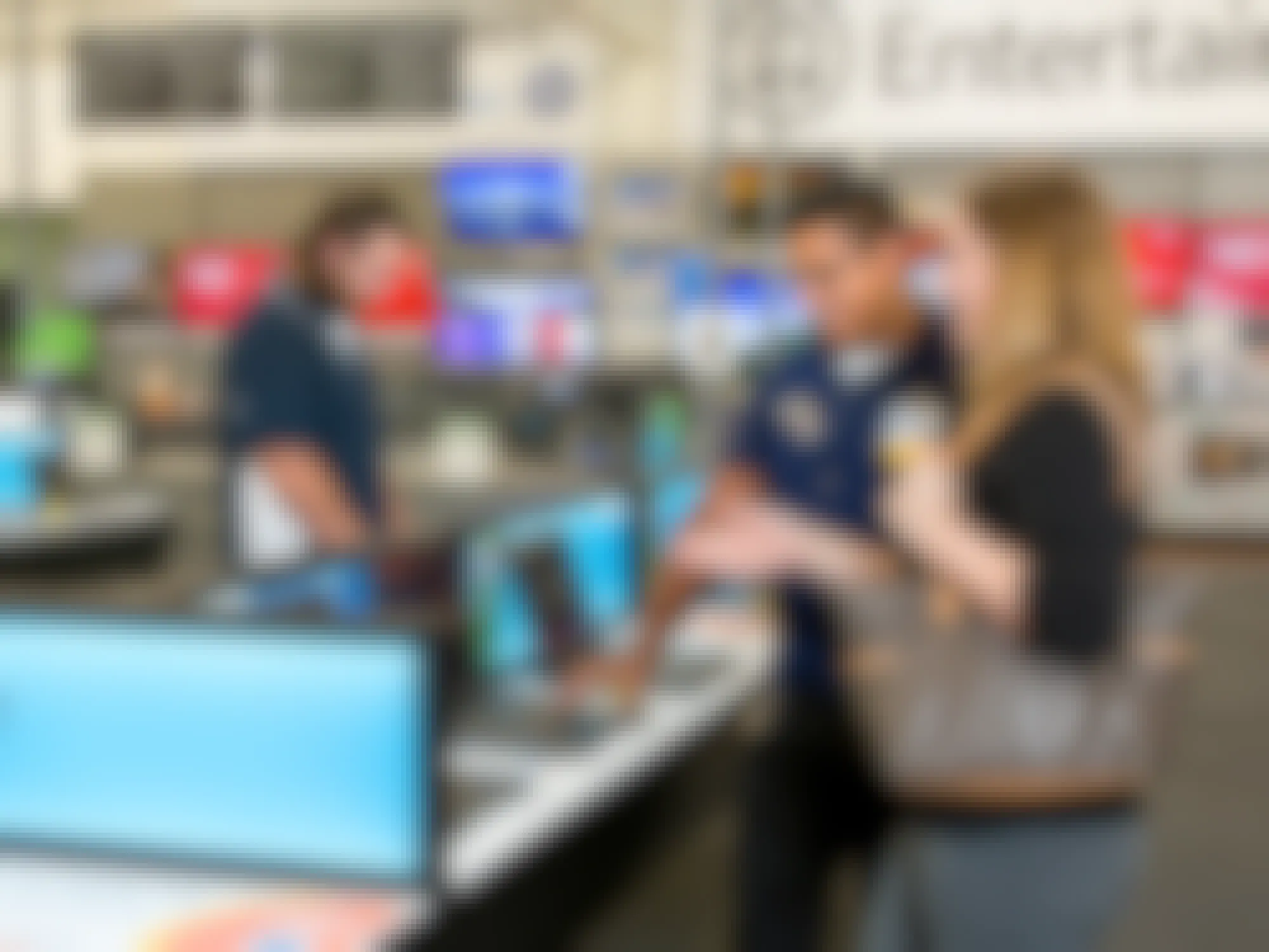 A Walmart employee talking to a customer in the electronics department