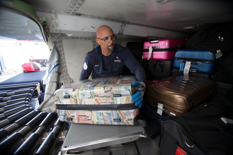 An American Airlines Fleet Service employee loading luggage onto a plane.