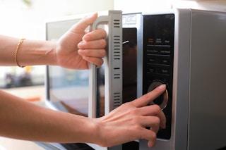 Person using and opening a microwave