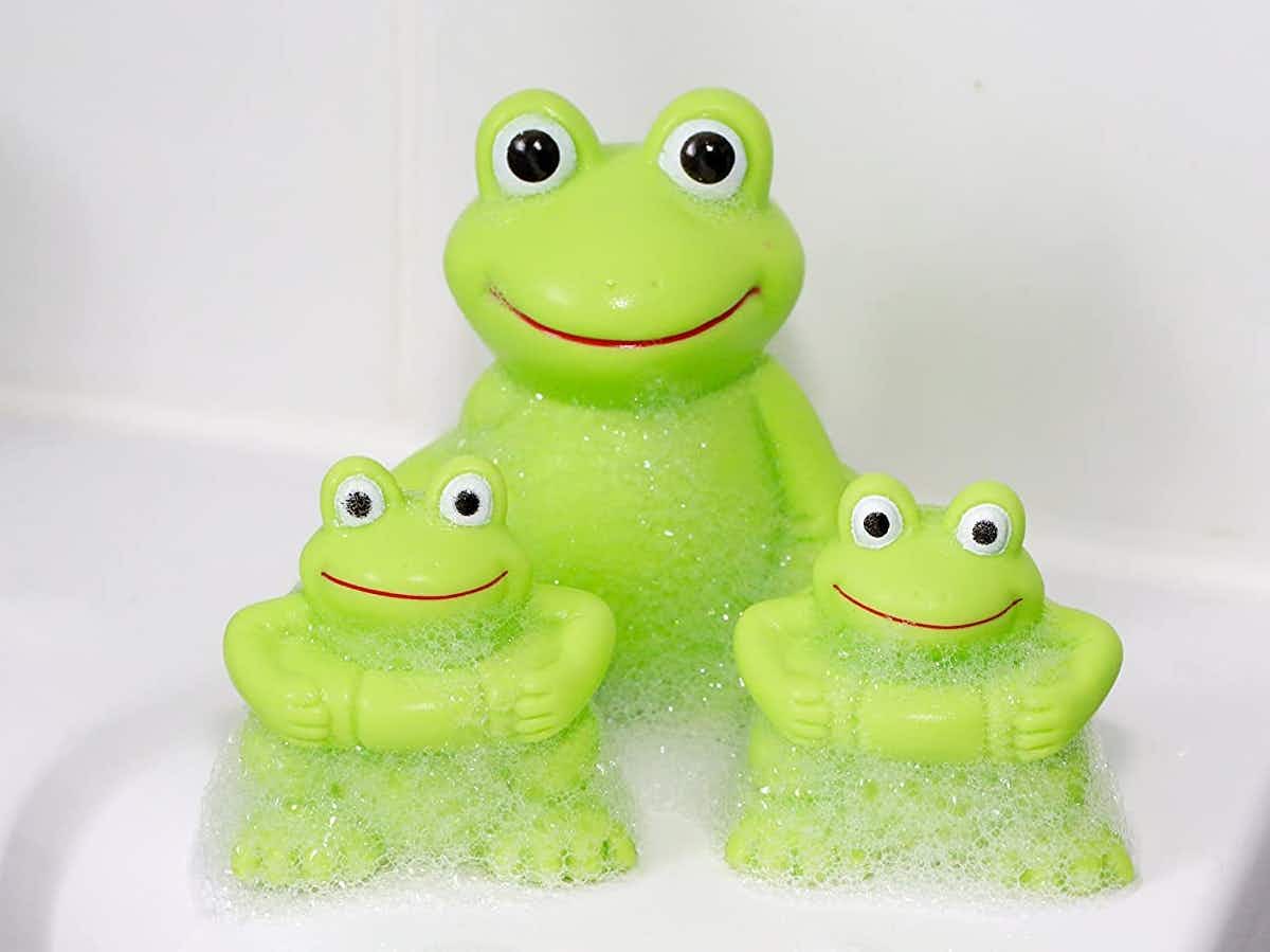 A Vital Baby Play 'n' Splash Family of Frogs, 3-pack covered in suds on the side of a tub