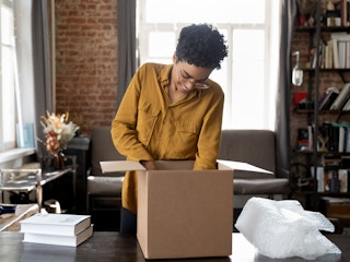 person packing books into box at home