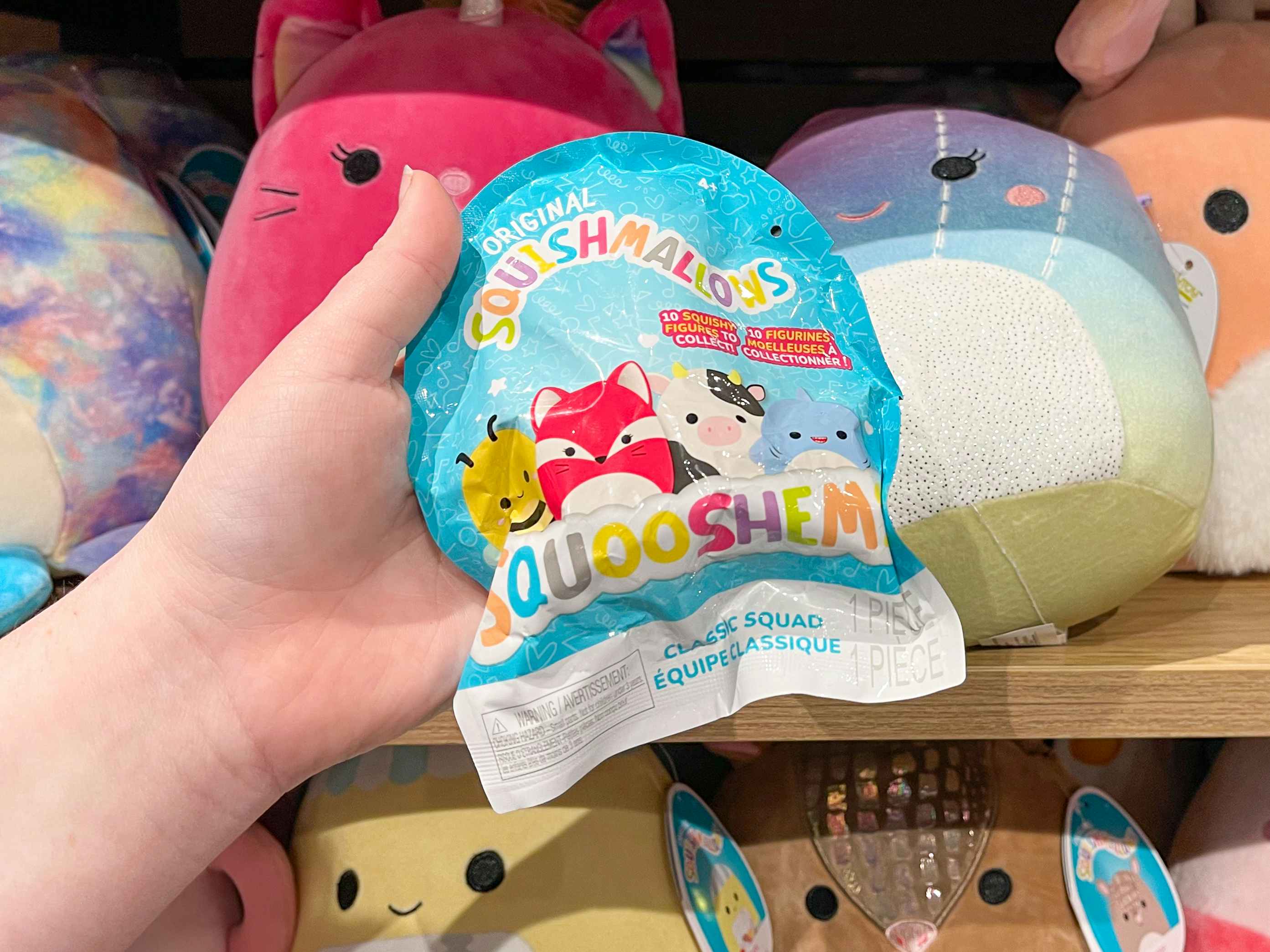 A person's hand holding up a Squishmallows Squooshem mystery blind bag