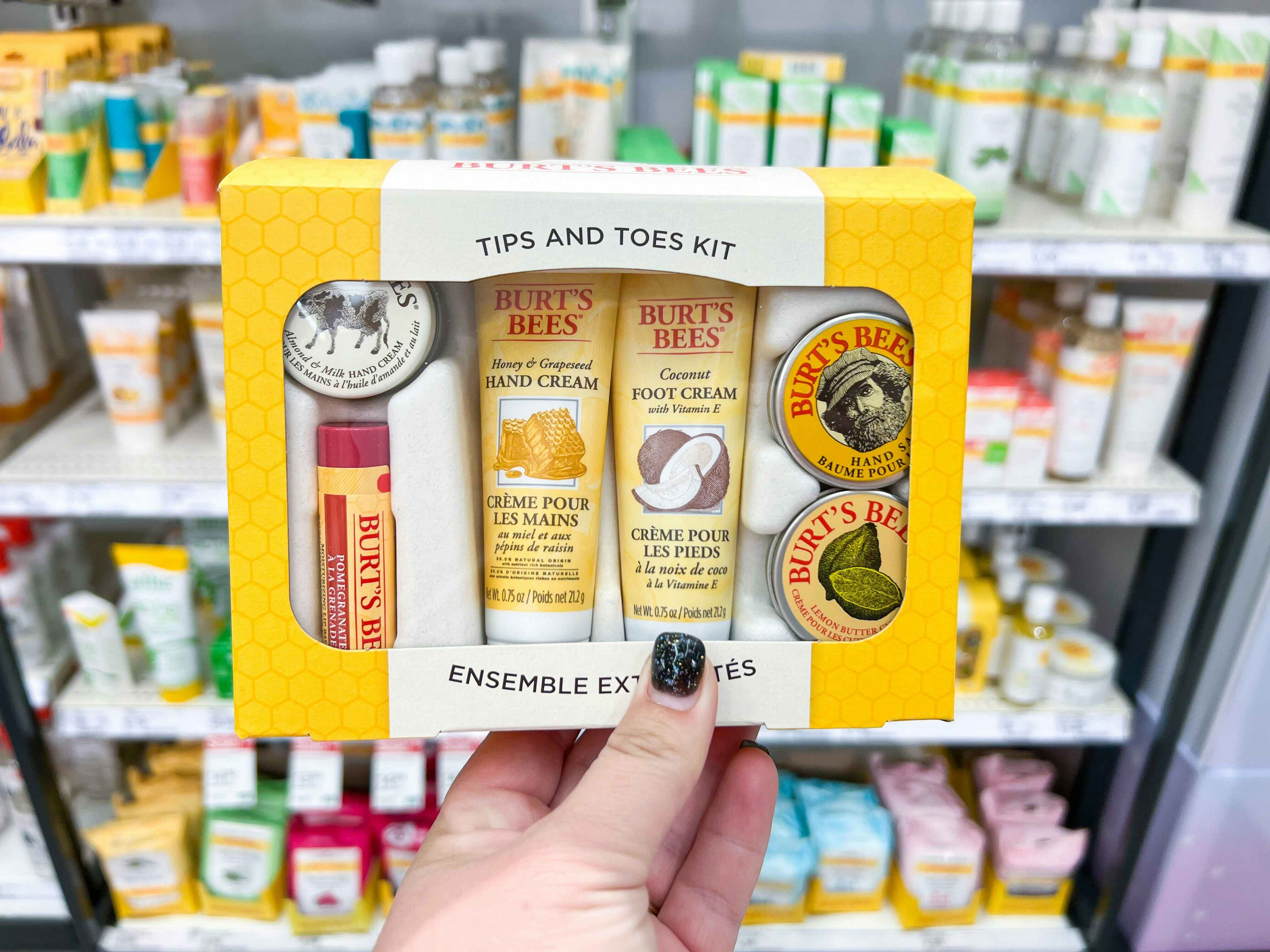 Hand holding a Burt's Bee's Tips And Toes Kit in front of other Burt's Bees products