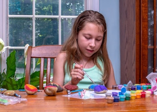 Child painting on rocks at home