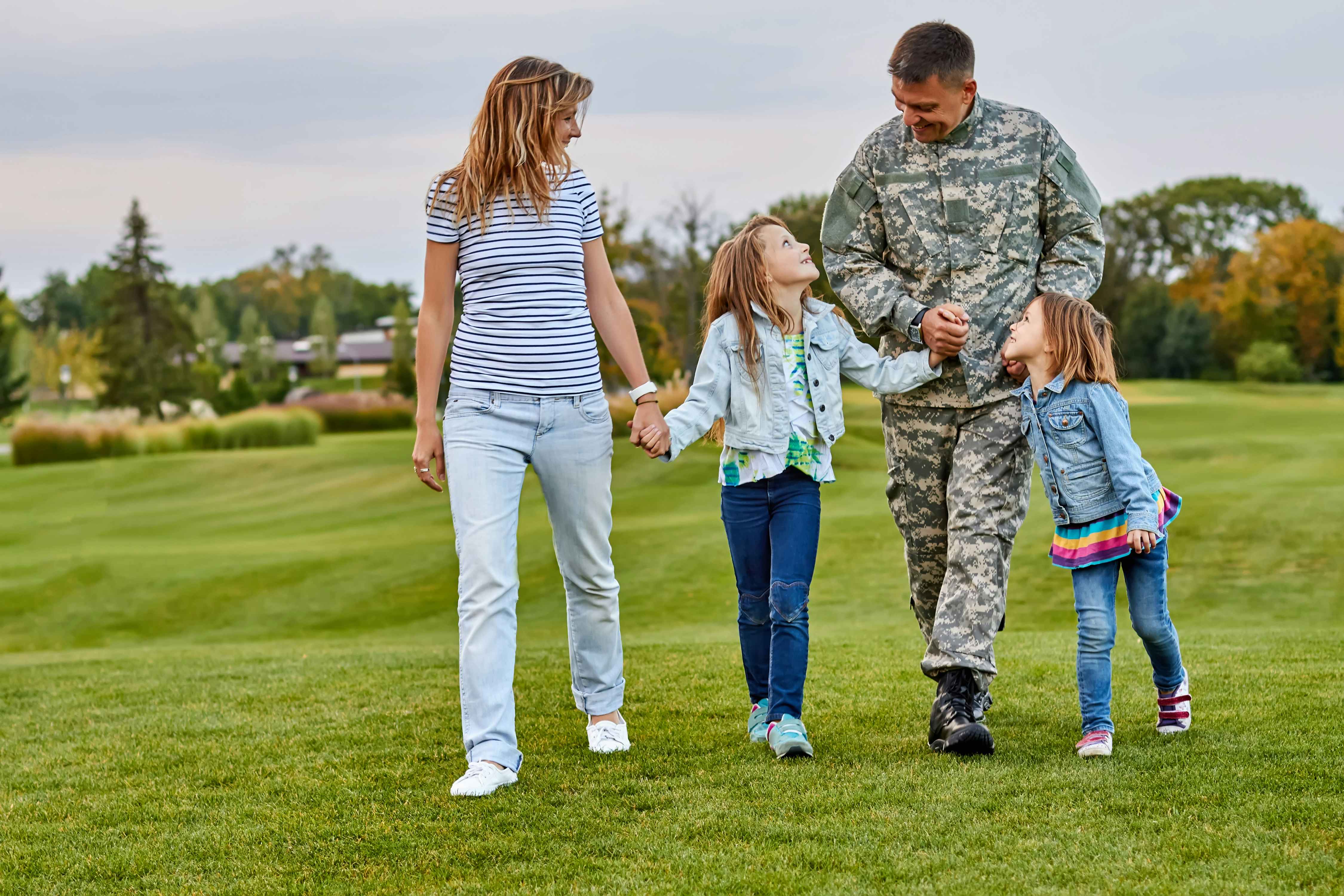 Person in Uniform with family while walking on a large yard