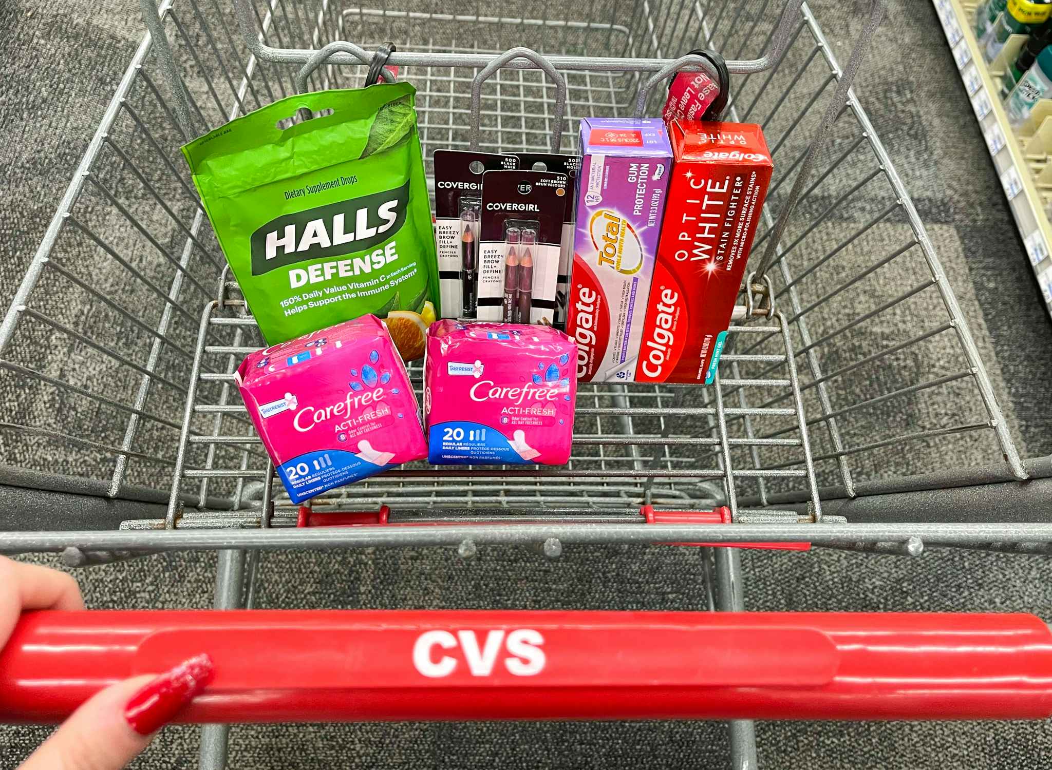 cvs shopping cart with halls, carefree, covergirl, and colgate with hand on handle