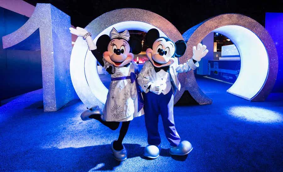 Mickey and Minnie Mouse mascots standing in front of a large 100 sign for the platinum celebration