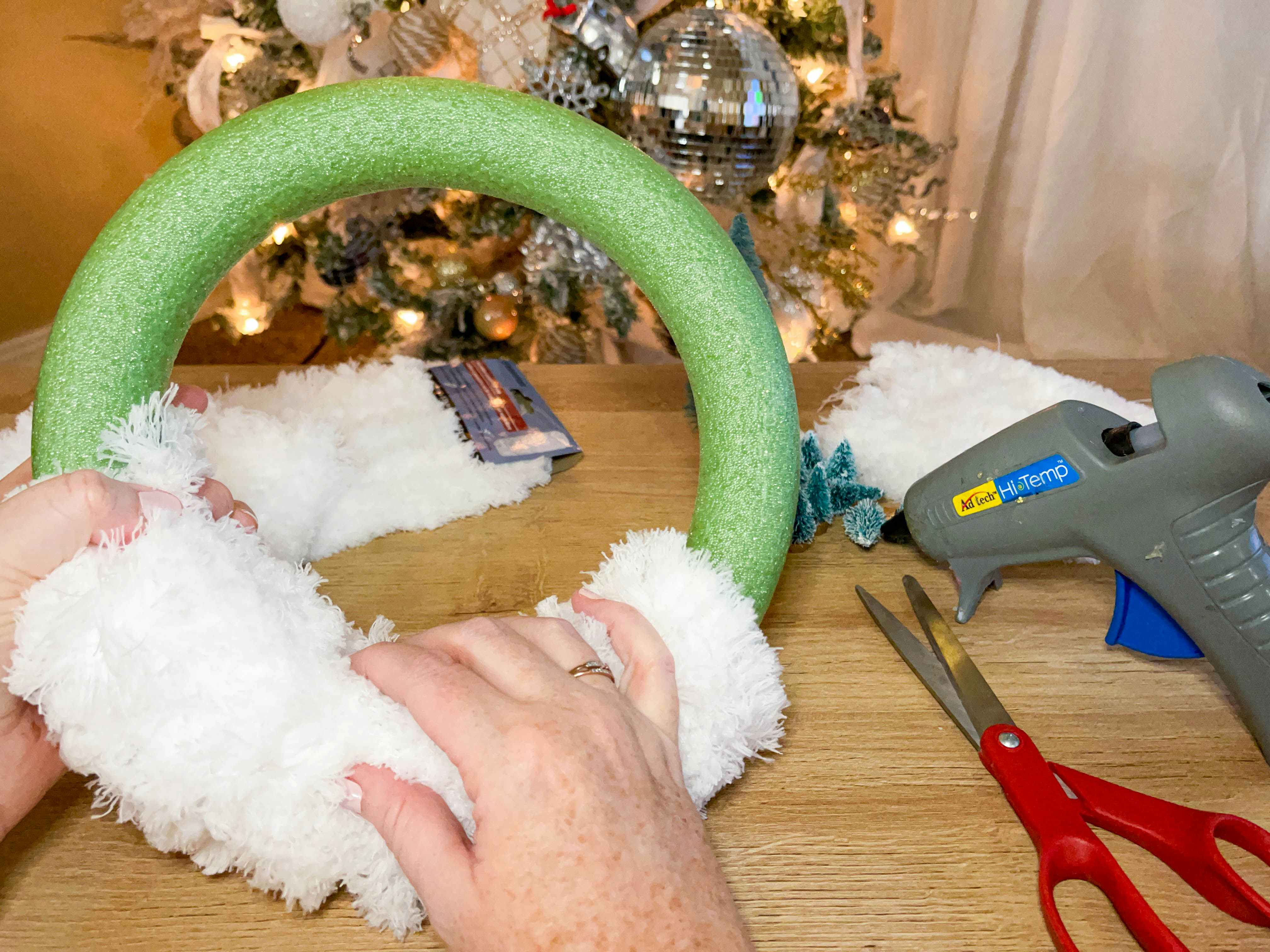 a person gluing mops on a wreath form 