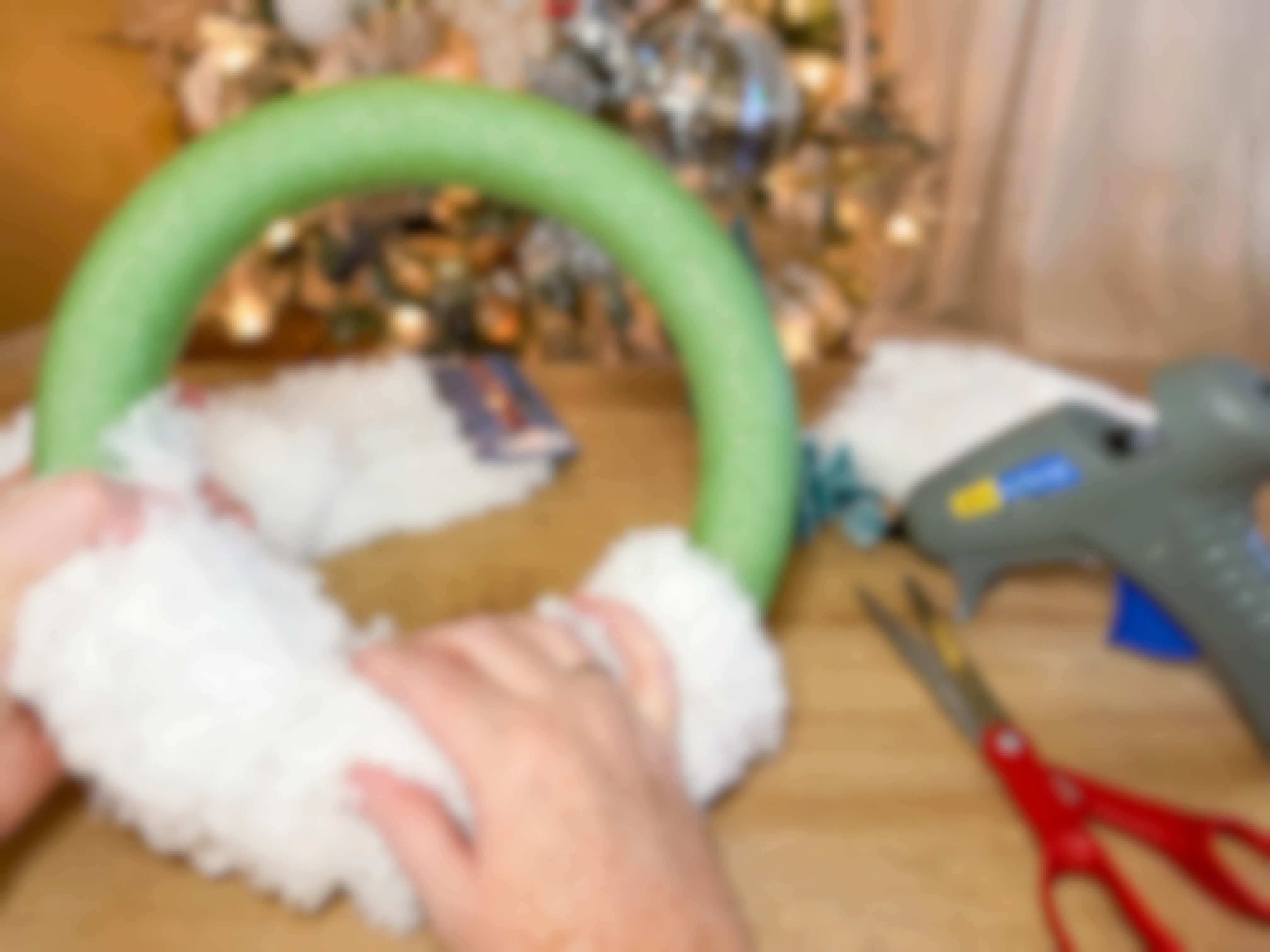 a person gluing mops on a wreath form 