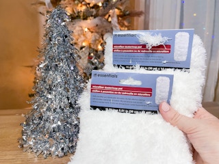 two white fuzzy mops being held in front of a tinsel mini tree