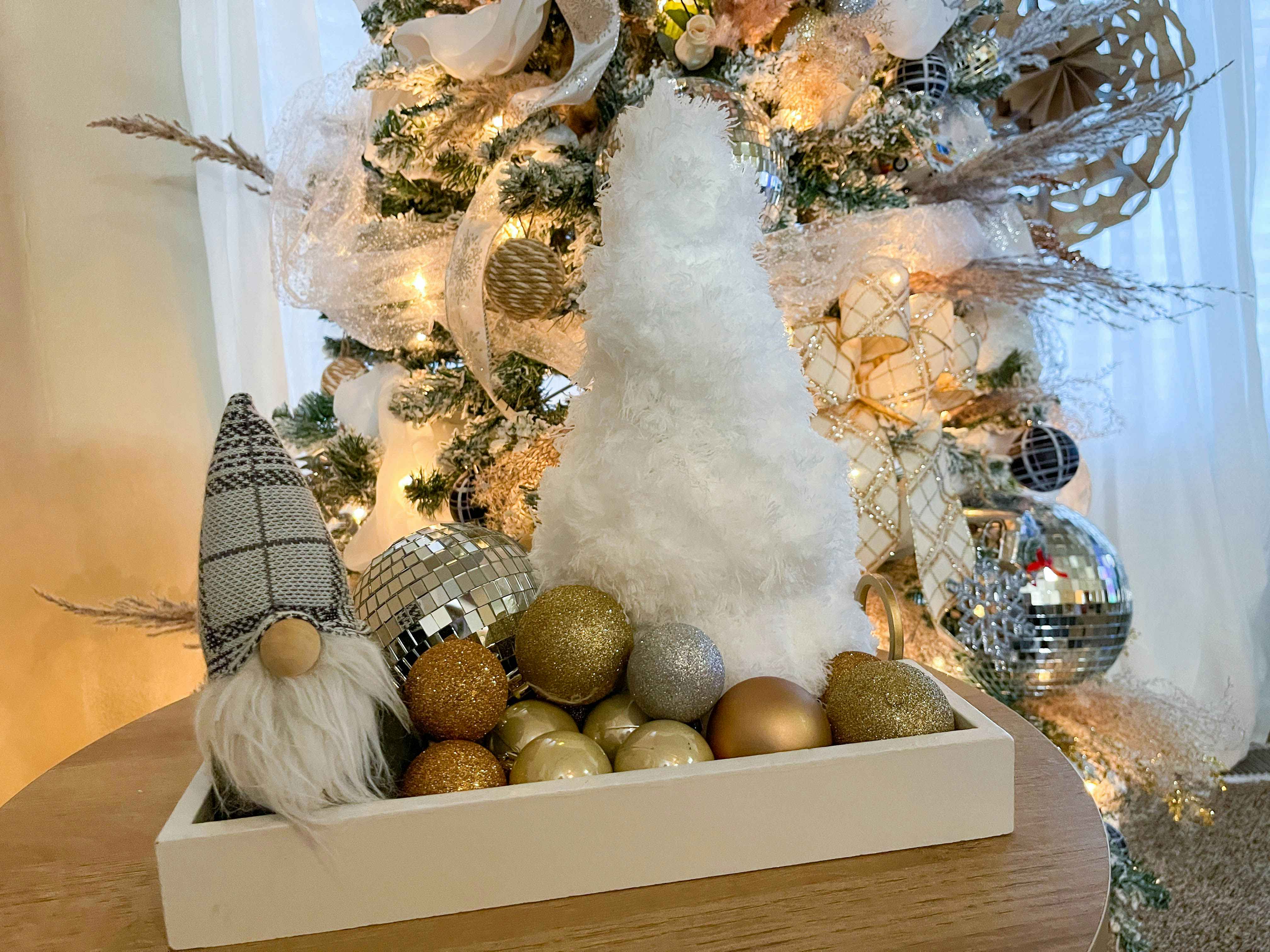 a fuzzy mop tree in a tray in front of a christmas tree 