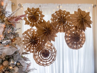a bunch of paper bag snowflakes hanging in a window 