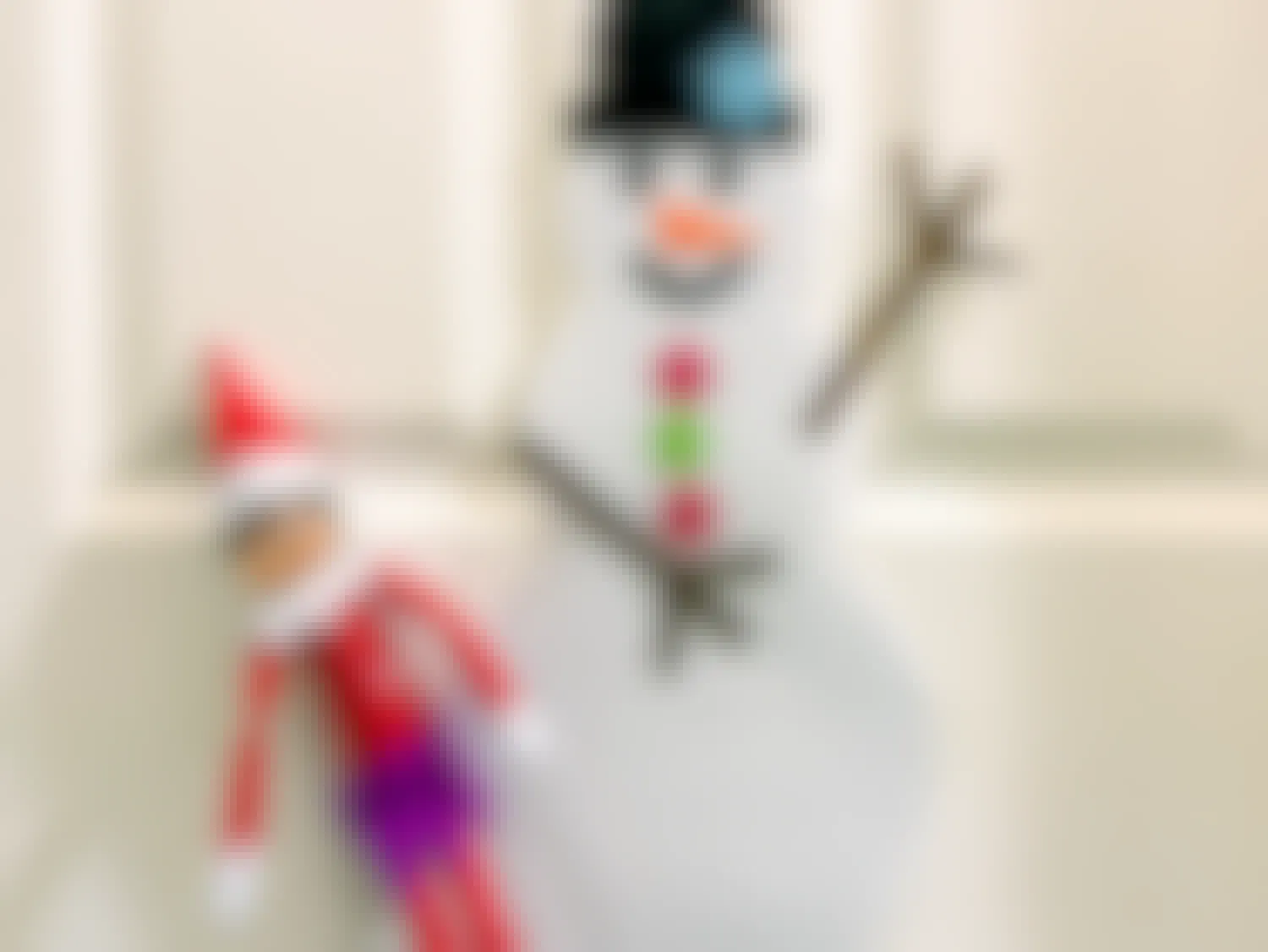 elf on the shelf hanging near decorated snowman on door